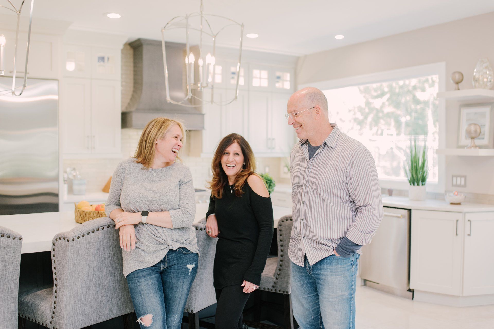 A group of people are standing in a kitchen talking to each other.