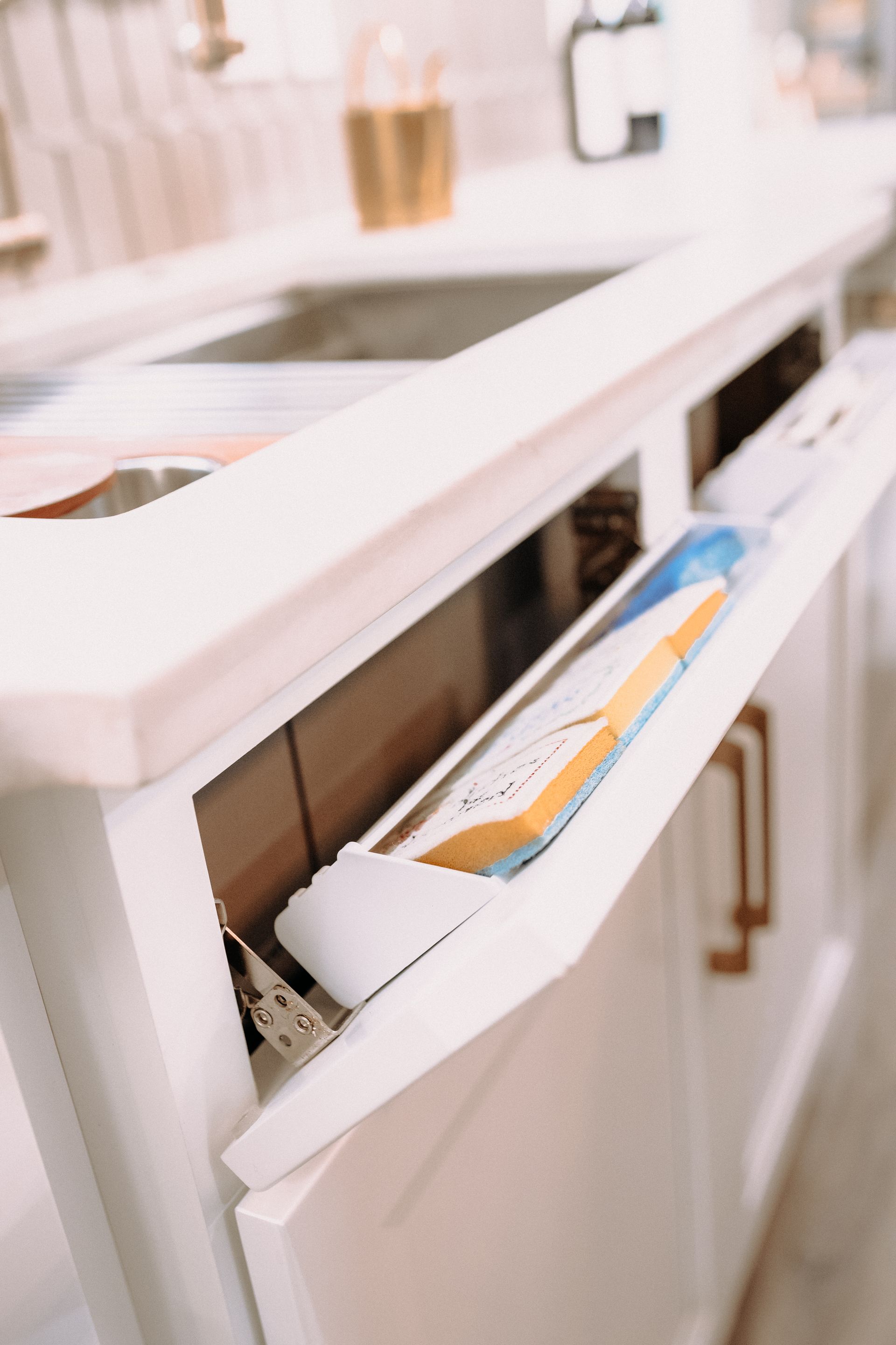 A kitchen sink with the door open and a box in it