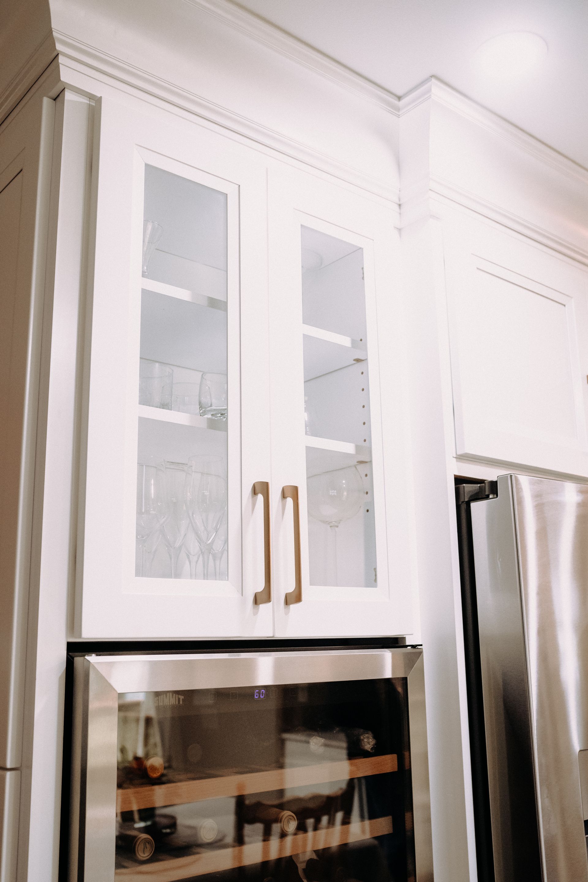 A kitchen with stainless steel appliances , white cabinets , and a wine cooler.
