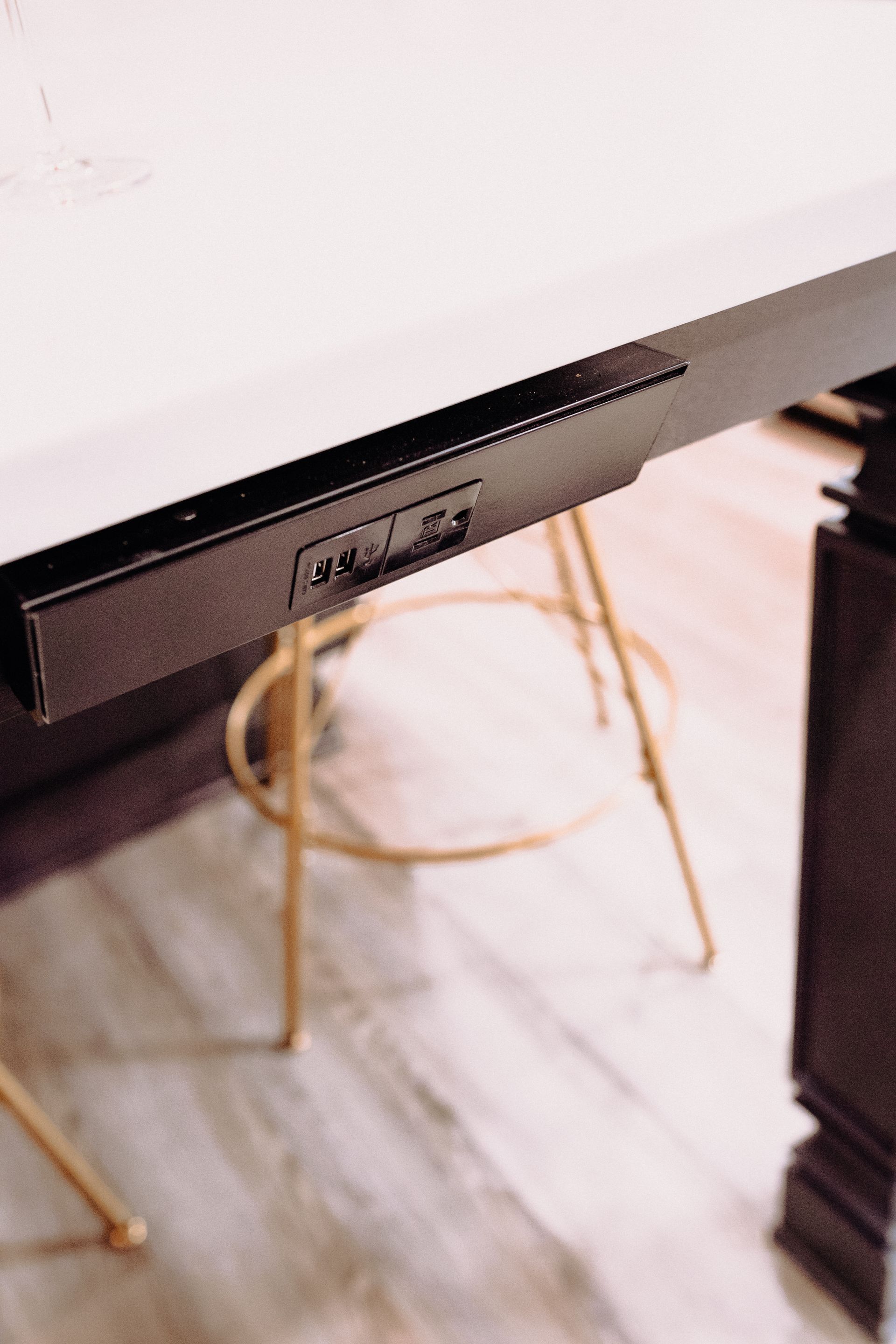 A black table with a white top has a few outlets underneath it