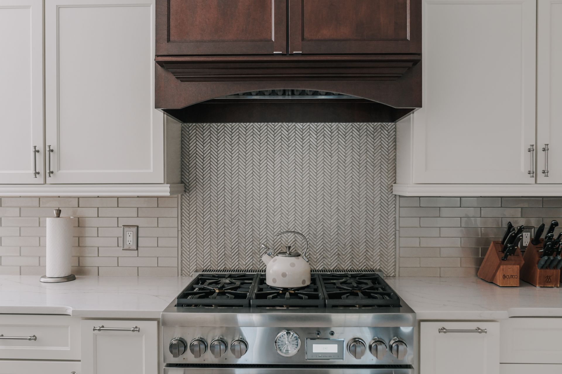 A kitchen with a stove top oven and a tea kettle on it.