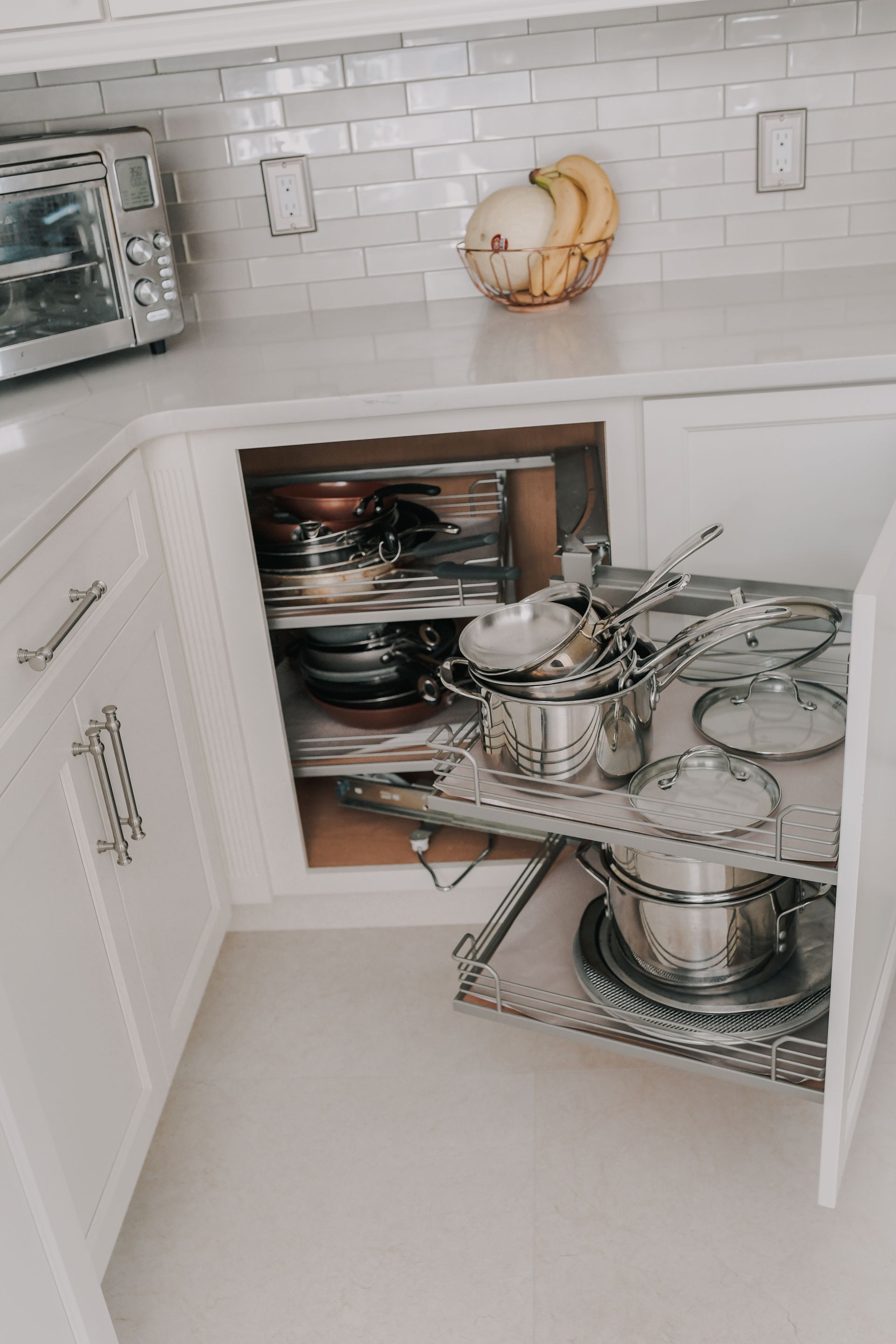A kitchen with a corner cabinet filled with pots and pans.