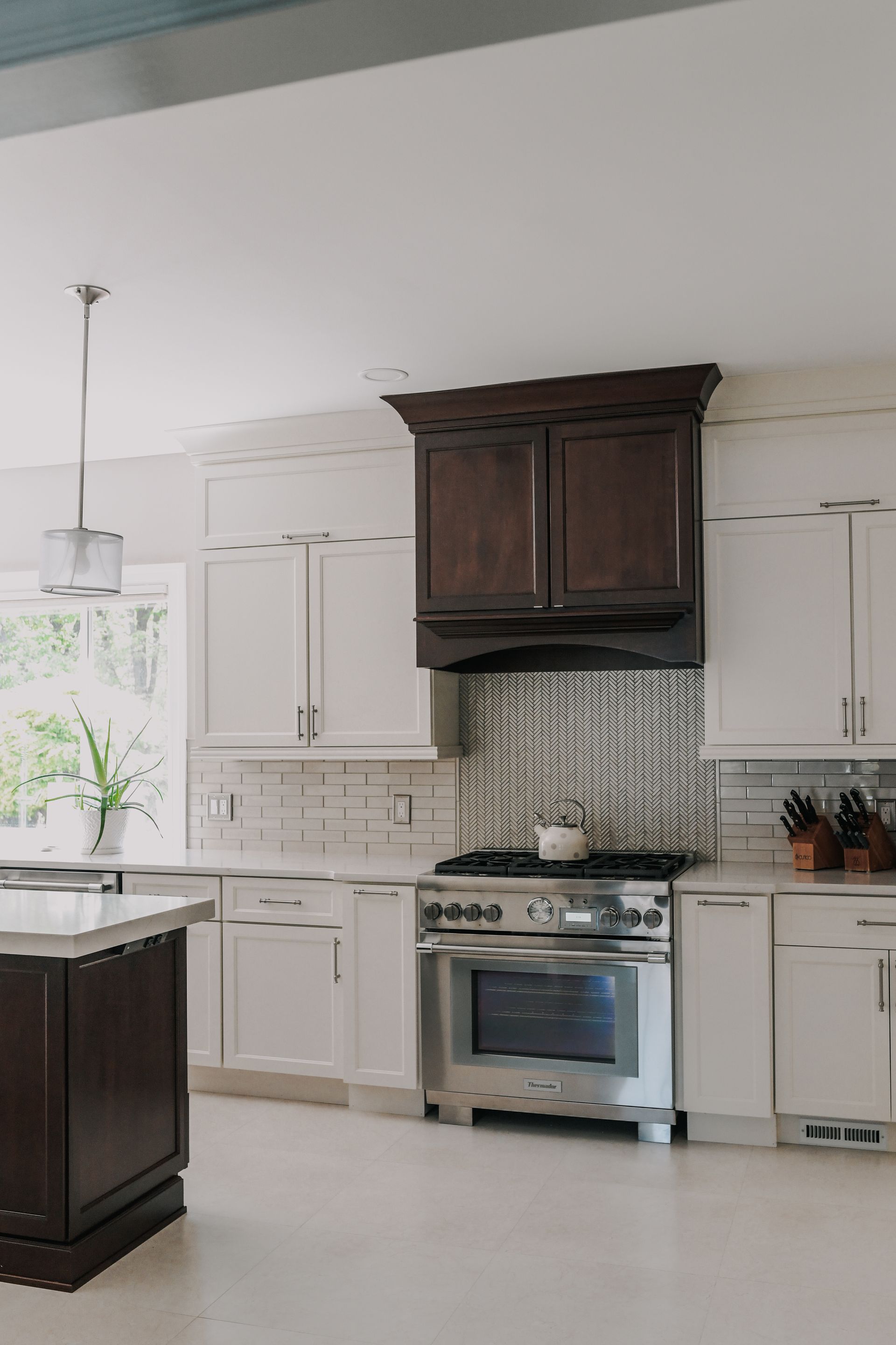 A kitchen with white cabinets , stainless steel appliances , and a large island.