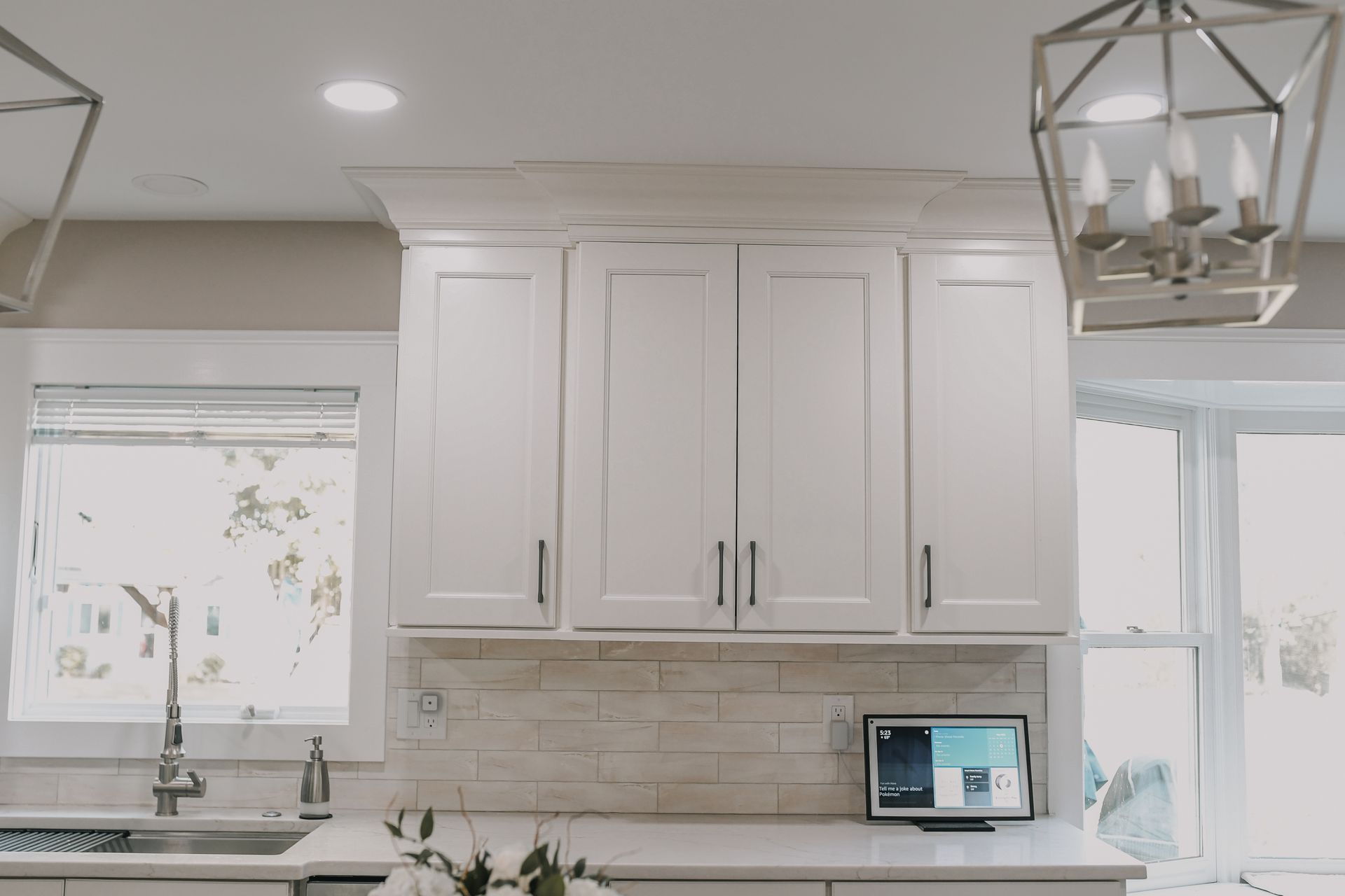 A kitchen with white cabinets , a sink , and a window.