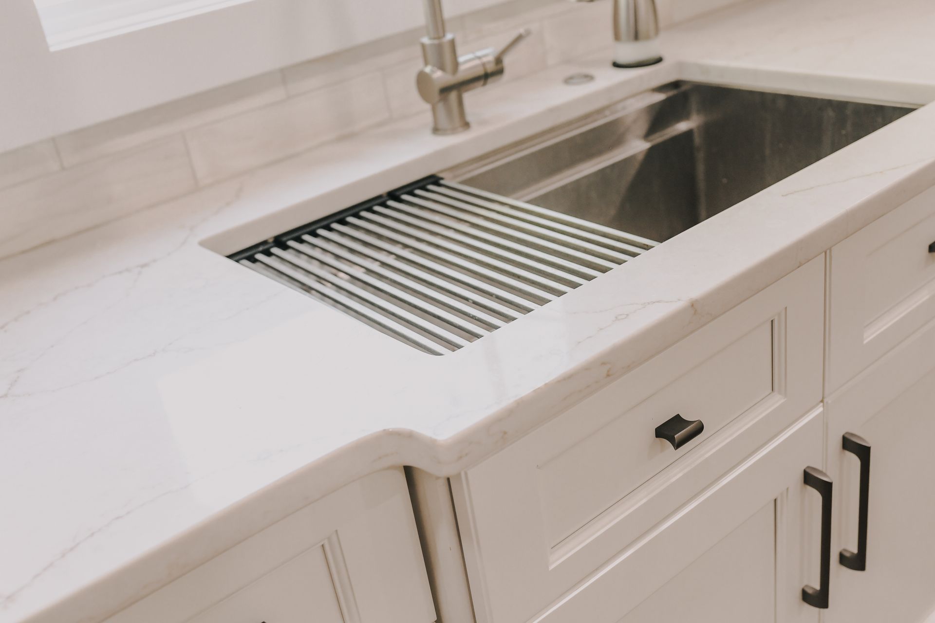 A kitchen sink with a stainless steel drain rack on top of it.