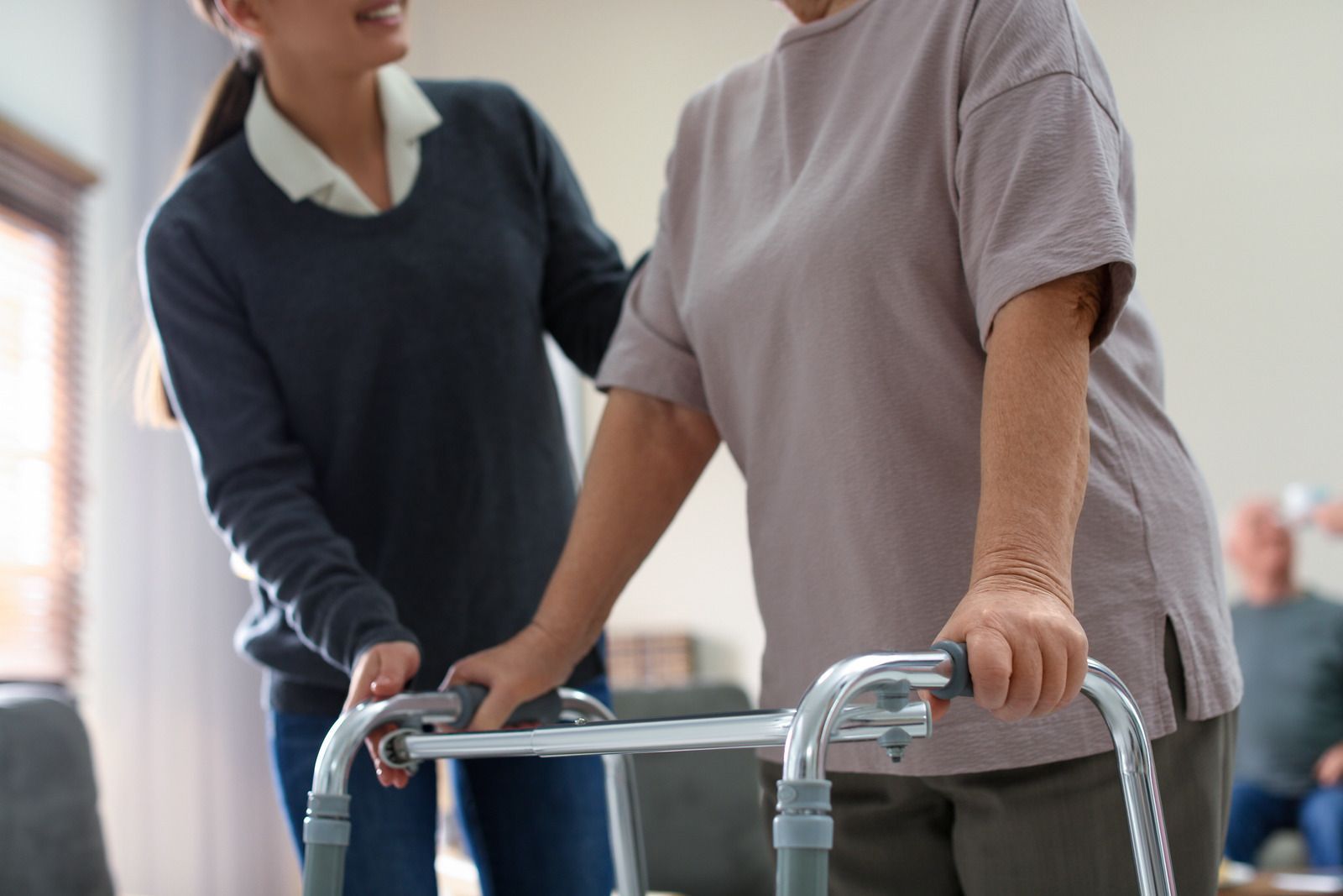 A woman is helping an elderly woman use a walker.