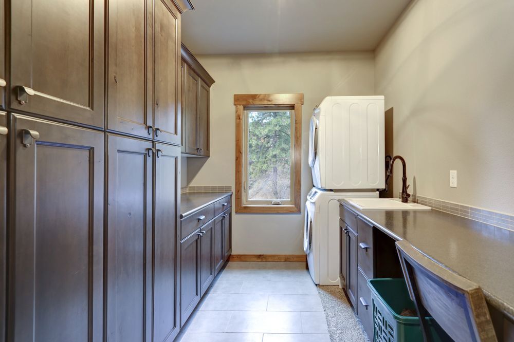 A Laundry Room With Wooden Cabinets , a Washer and Dryer , a Sink , and a Window — Pacific Cabinets In Iluka, NSW