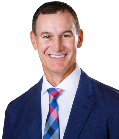 Man in a blue suit and patterned tie, smiling at the camera.