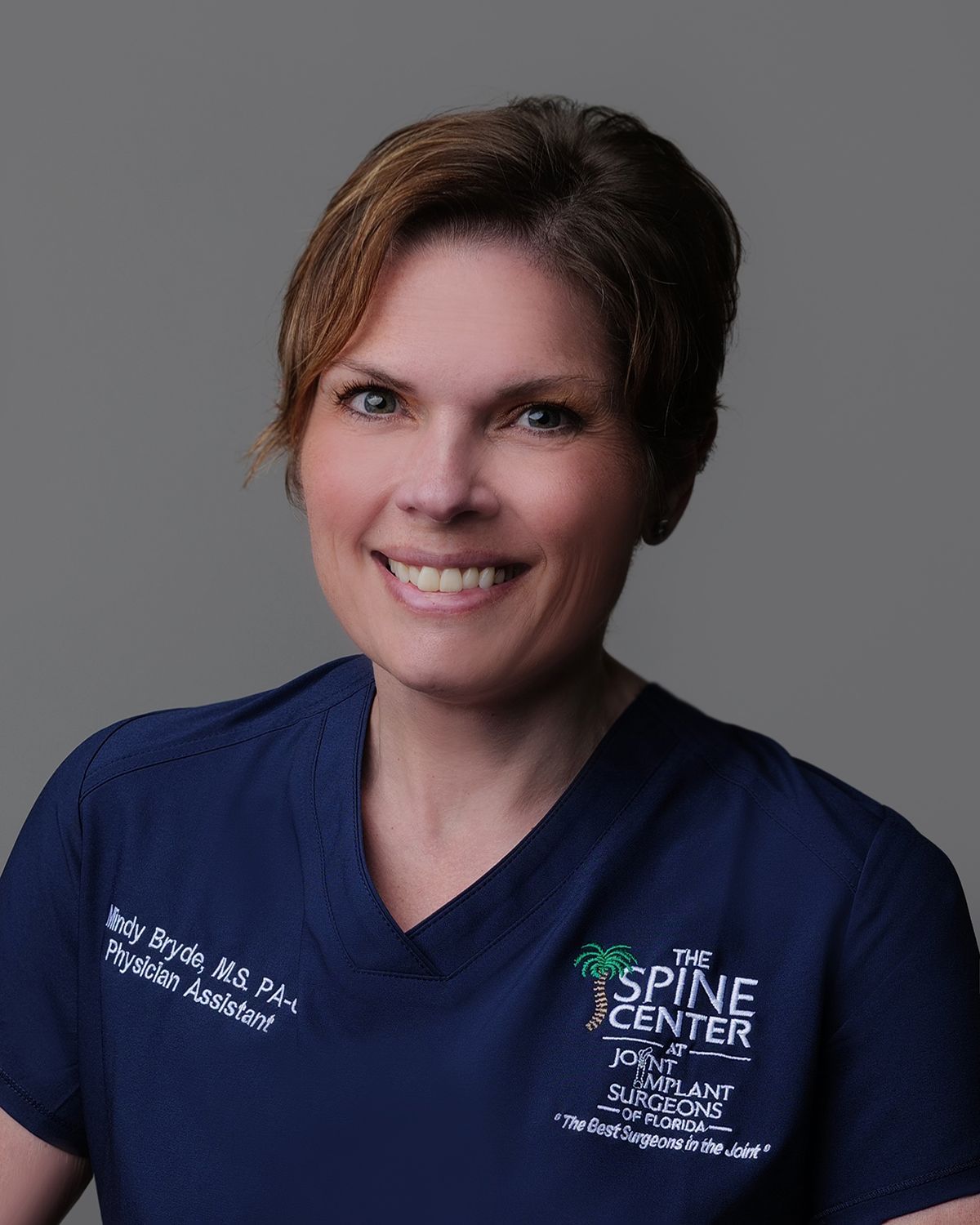 Woman, Dr. Rachel Ray, in white lab coat at The Spine Center. Smiling, brown hair.