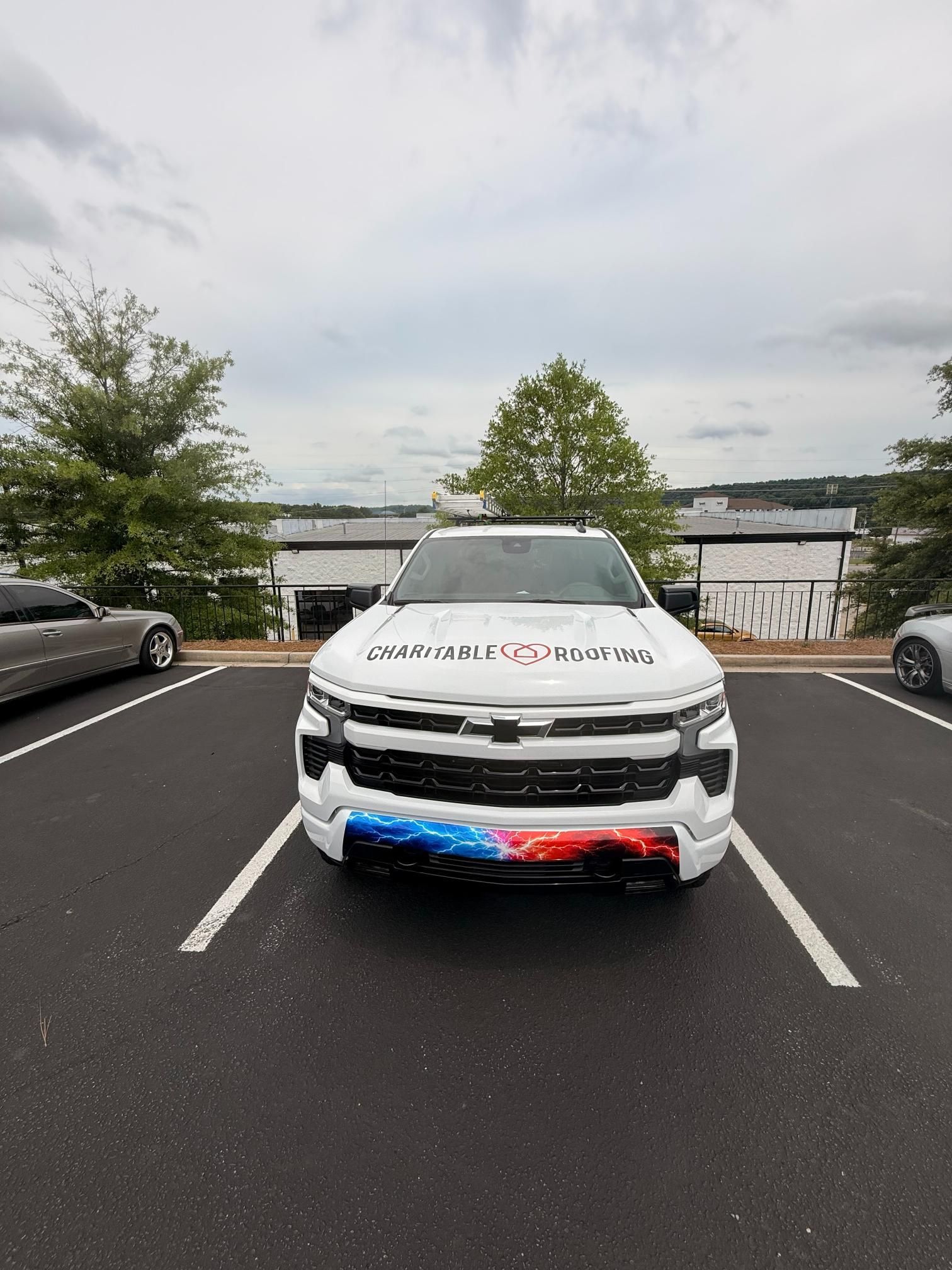 White SUV with red and blue bumper lights parked in a lot, viewed from the front.