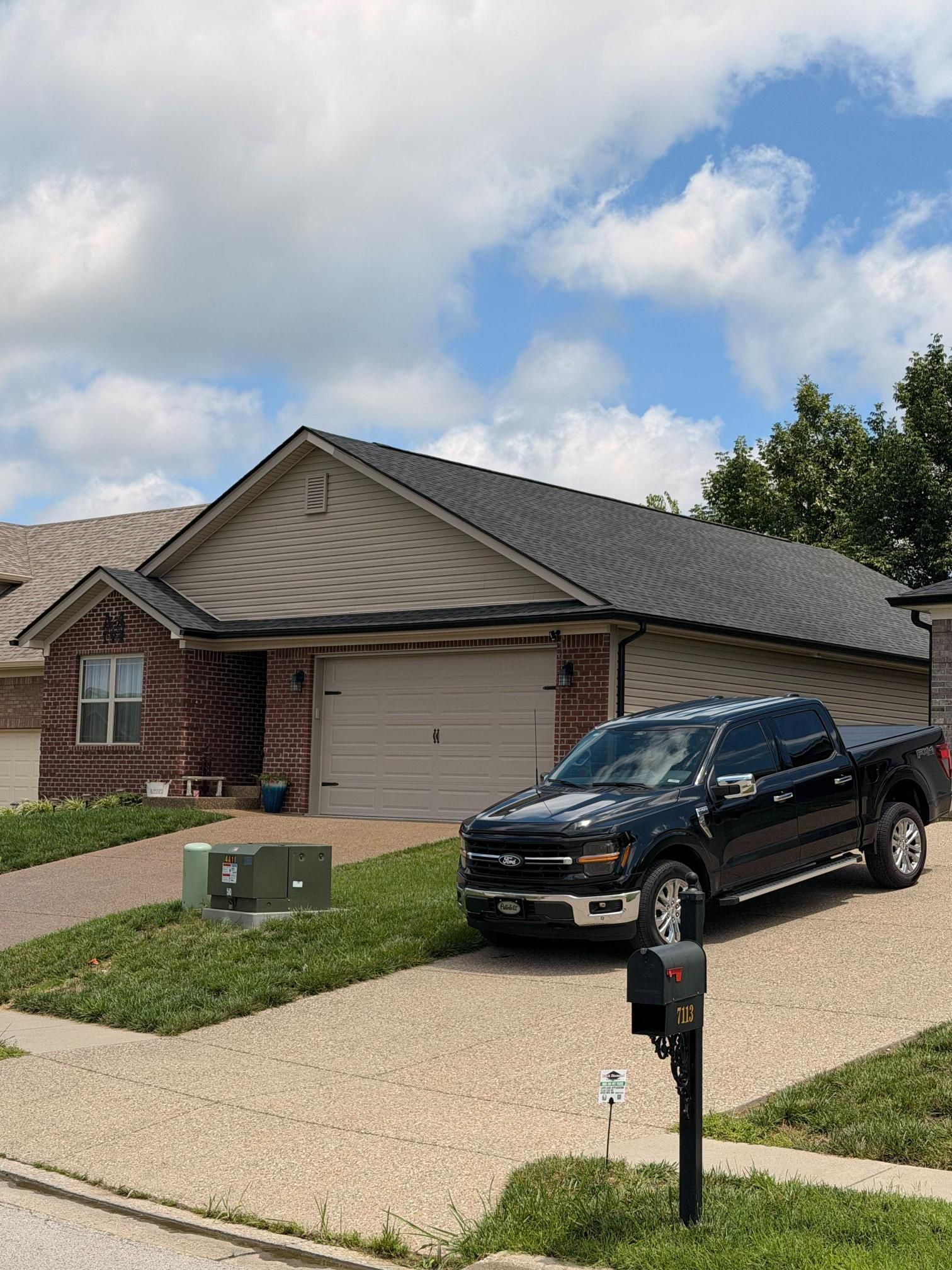 Suburban brick house with a black SUV parked in the driveway and a mailbox in front
