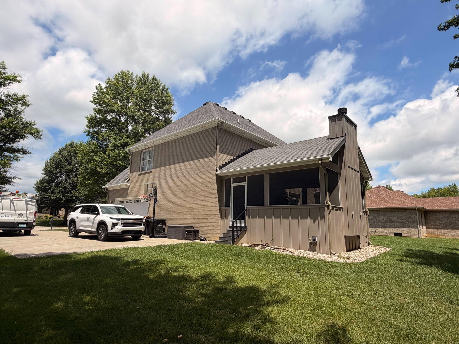 Suburban house with a white pickup truck parked on a grassy lawn under a partly cloudy sky