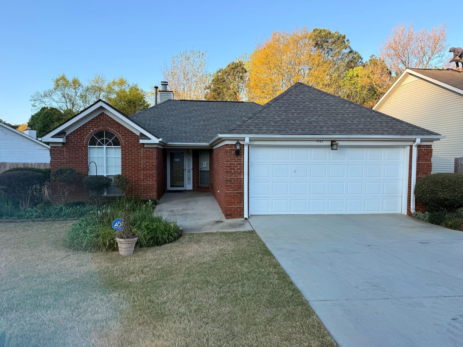 Single-story brick house with a white garage and driveway in a suburban neighborhood