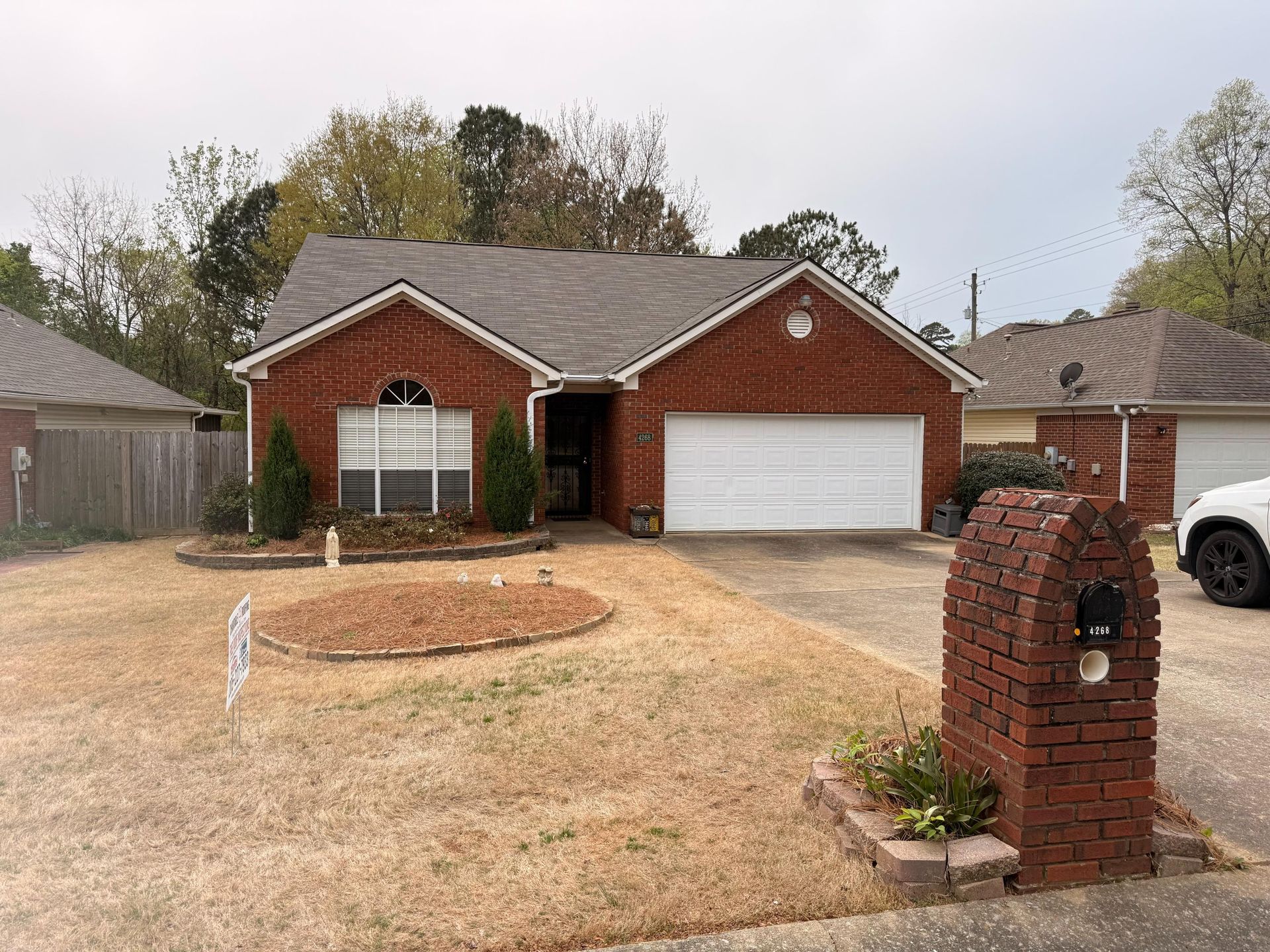 Brick suburban house with two-car garage, driveway, and a brick mailbox in the front yard.