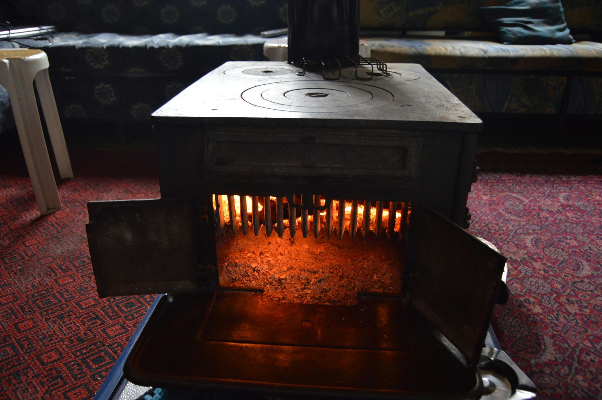 Wood-burning stove with open doors and glowing fire in a dim room