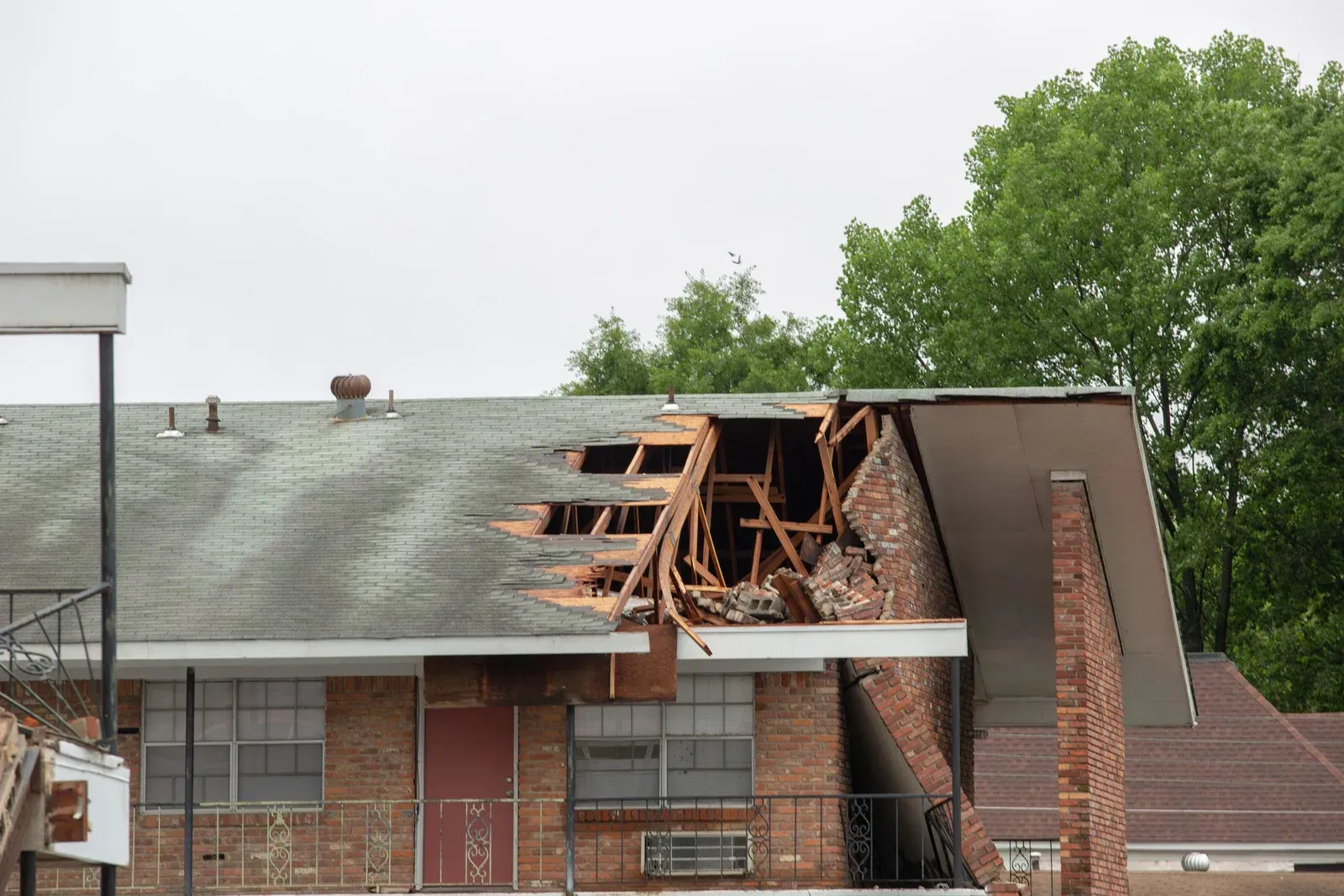 Partially collapsed brick building roof with exposed wooden beams and debris