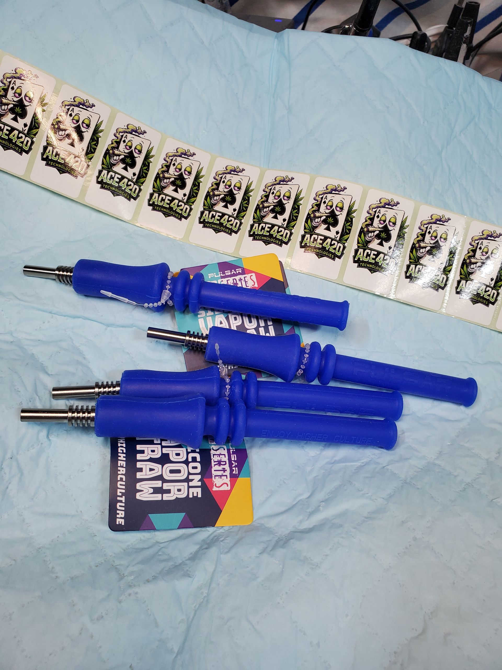 Blue pen-like tools and a colorful pack on a patterned fabric surface.