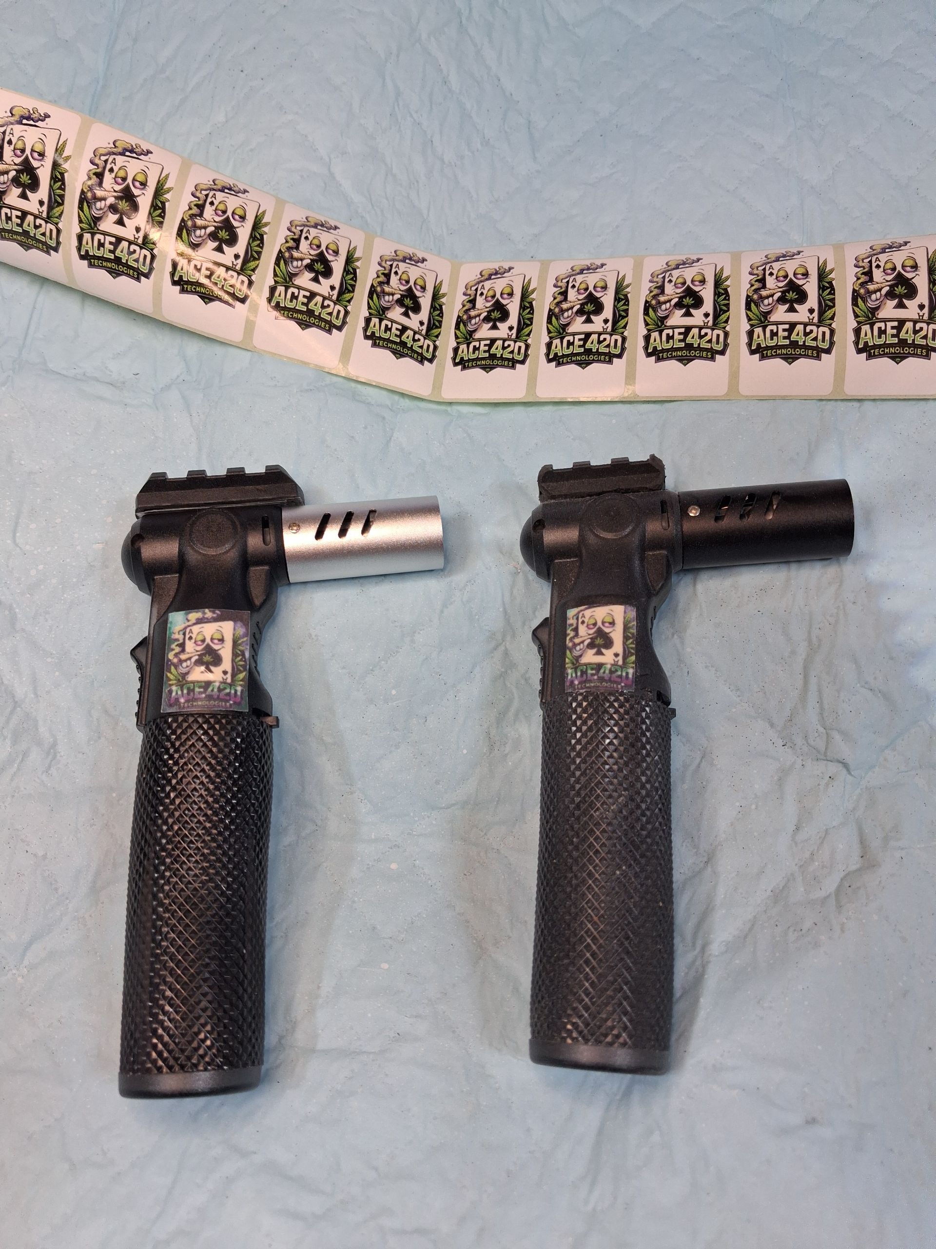 Two black handheld tools with textured grips and silver shafts beside a curved strip of small printed squares