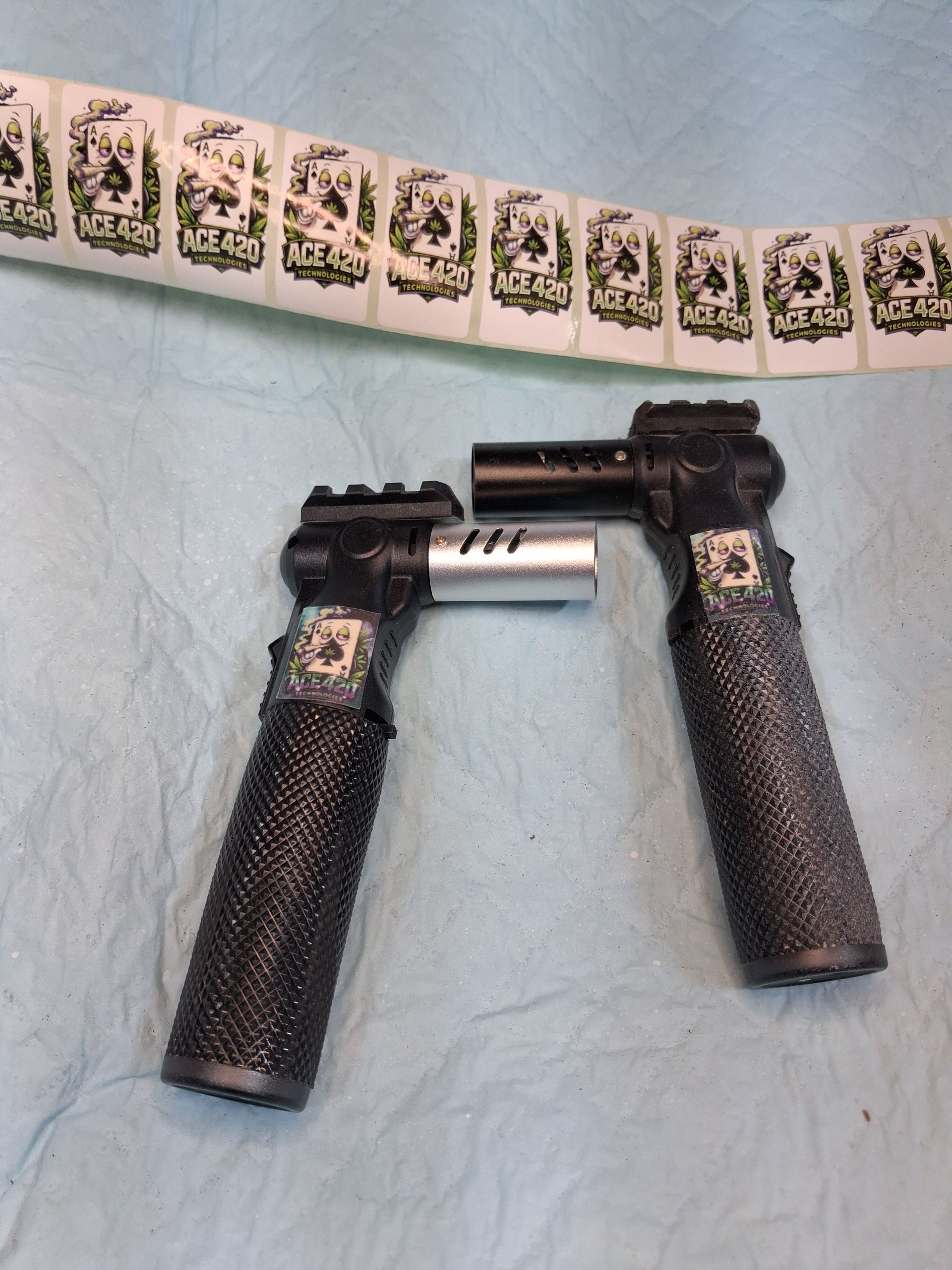 Two black handheld tools with textured grips and silver shafts beside a curved strip of small printed squares