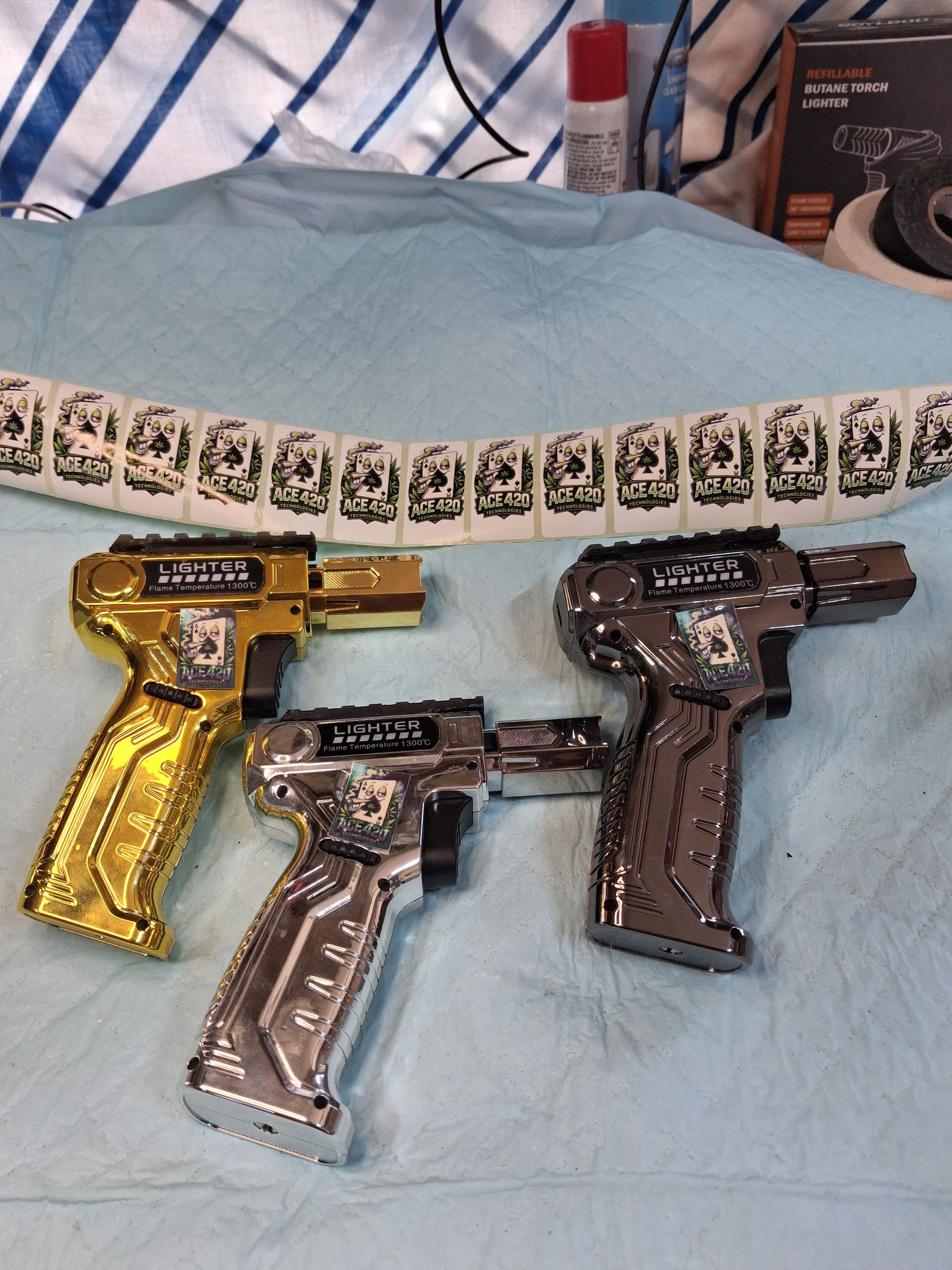Three toy pistols in gold, silver, and dark brown on a light blue blanket.