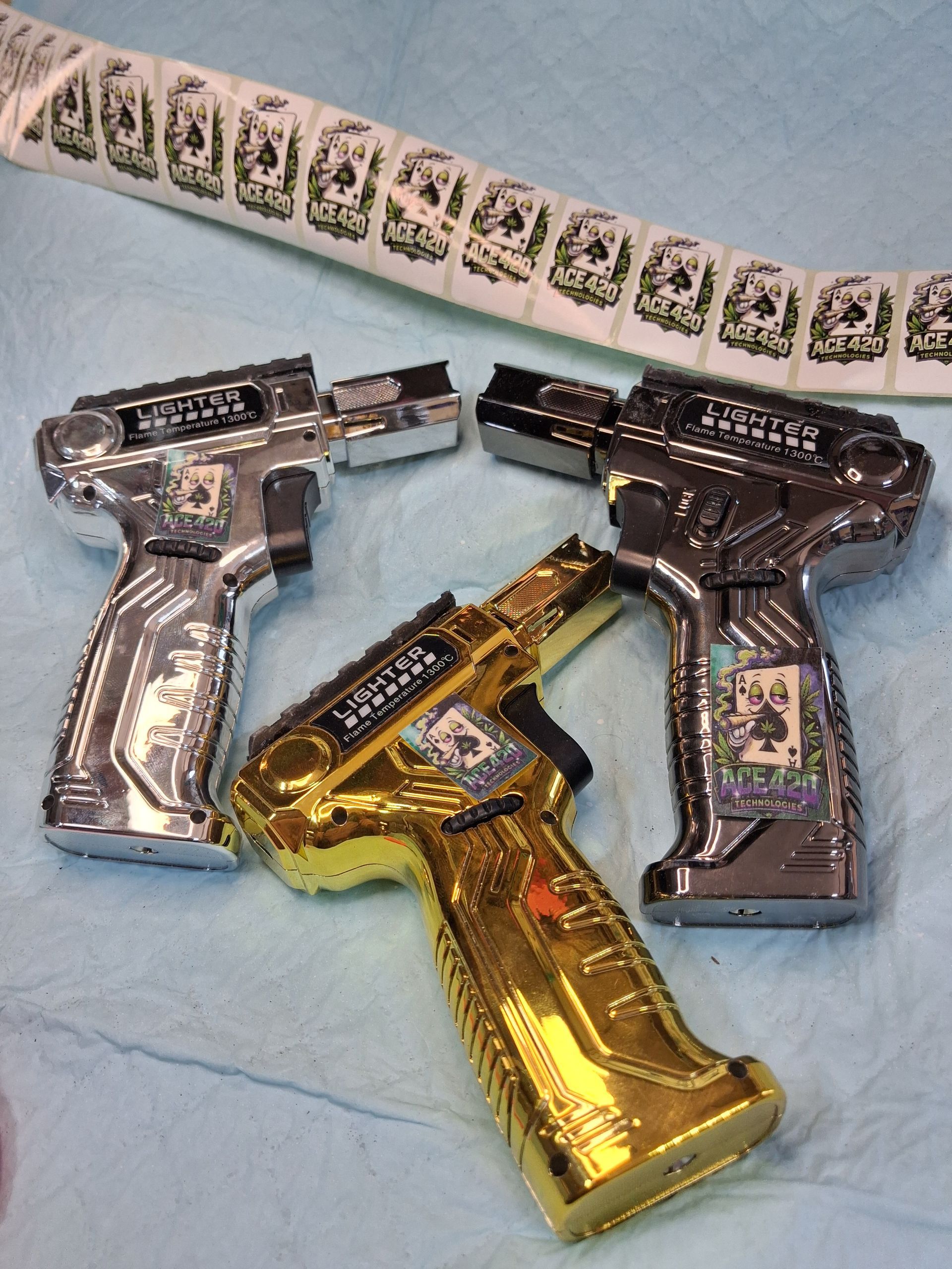Three toy pistols in gold, silver, and dark brown on a light blue blanket.