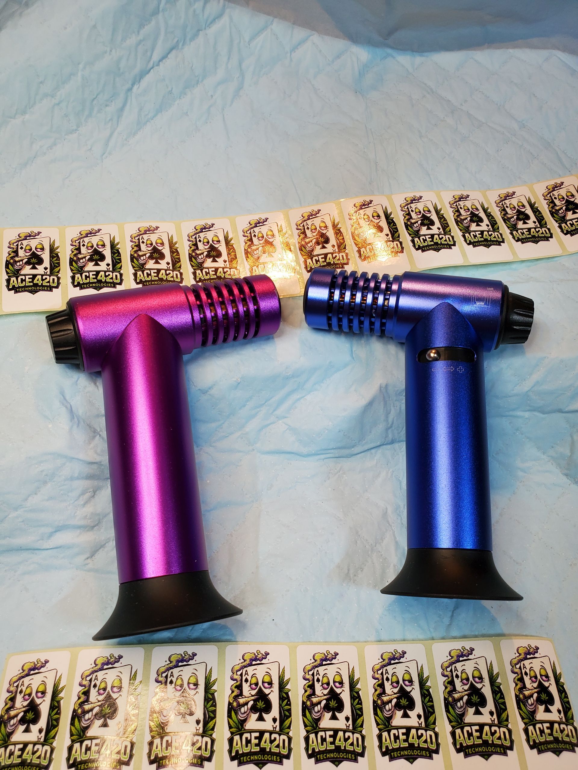 Two colorful metal T-shaped devices, one purple and one blue, laid on a blue cloth with card strips nearby