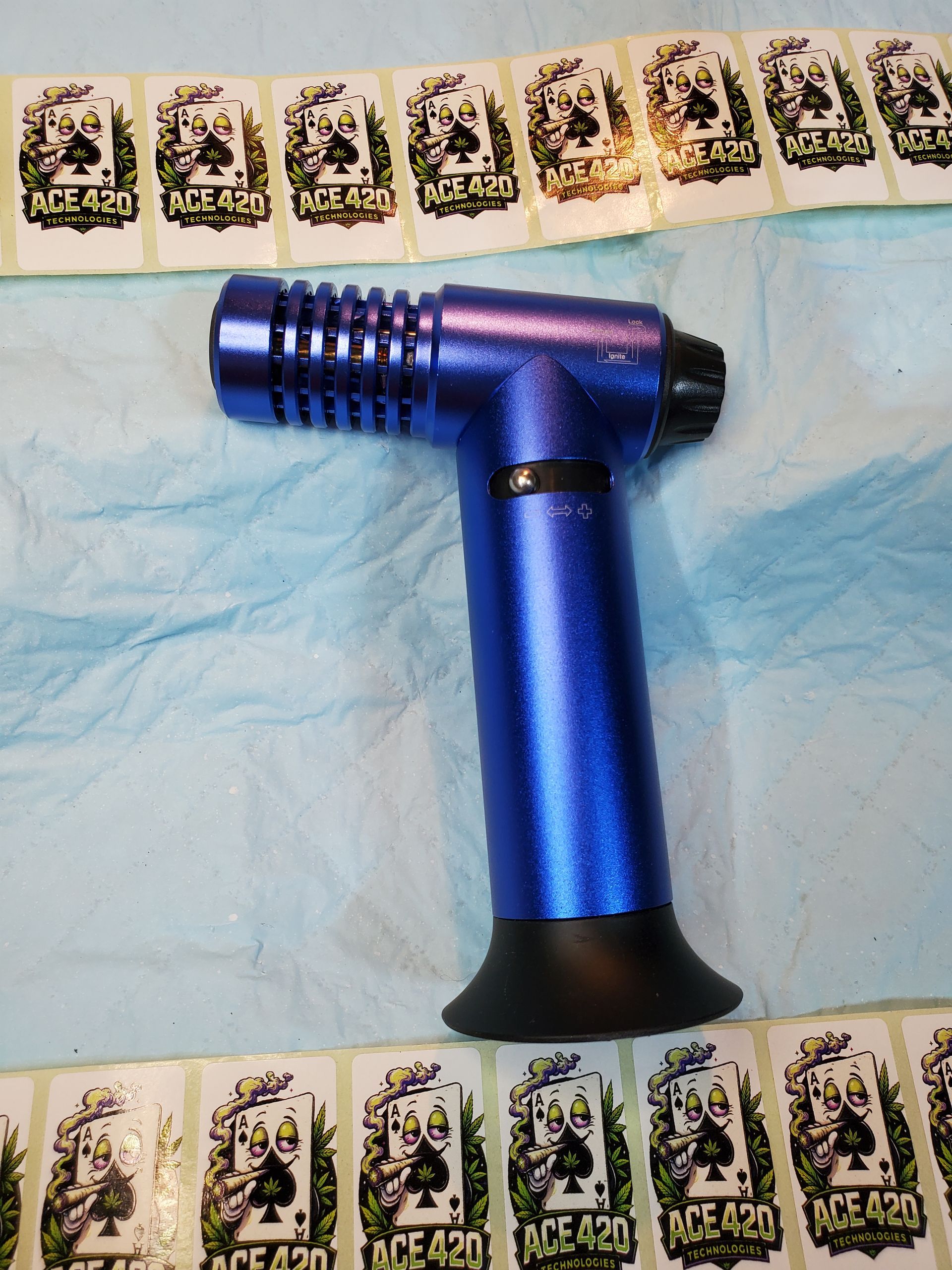 Blue butane torch lighter on a blue cloth, with a row of playing cards above and below it