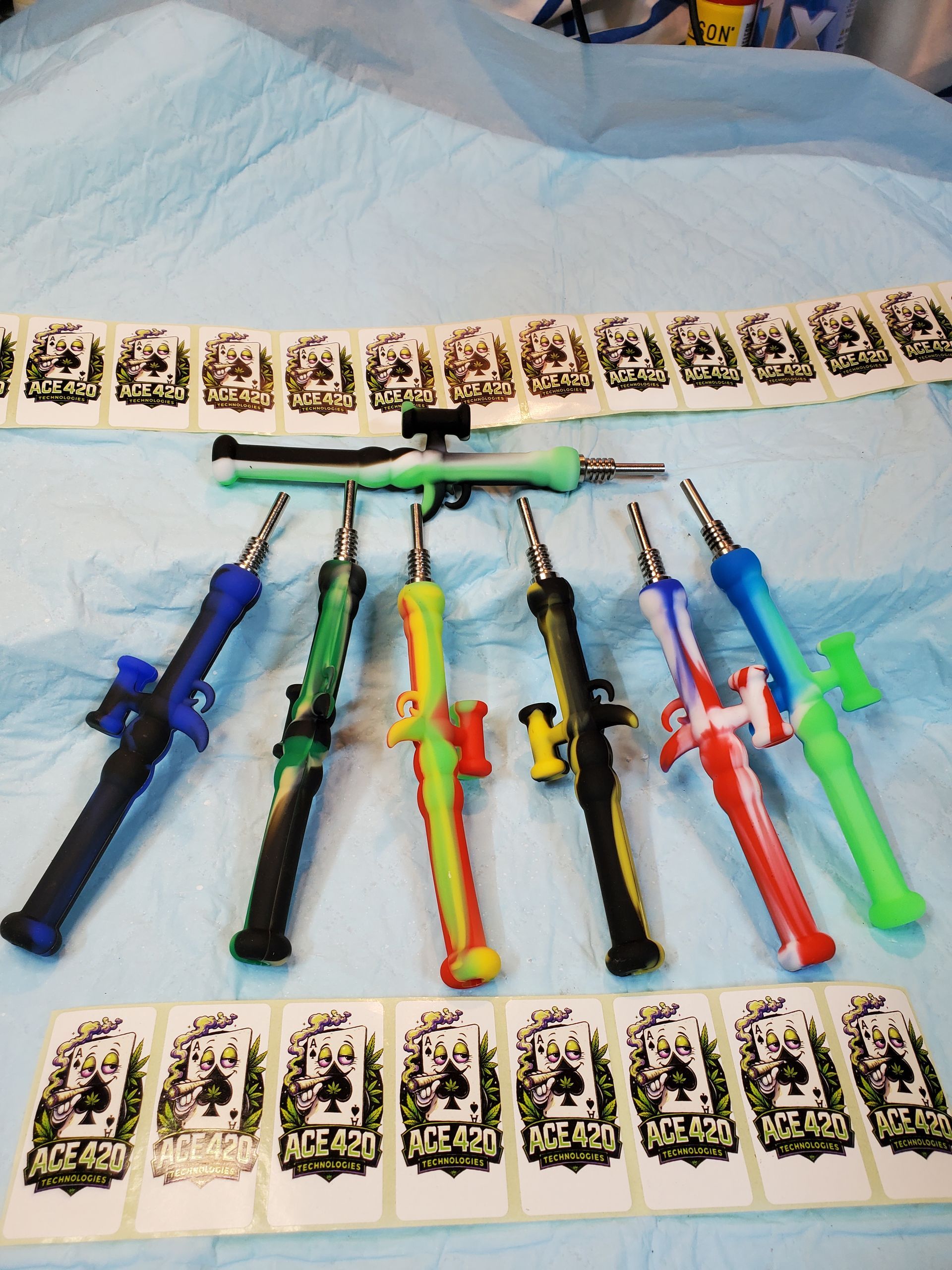 Assorted colorful toy swords and knives arranged on a bed with patterned cards above and below