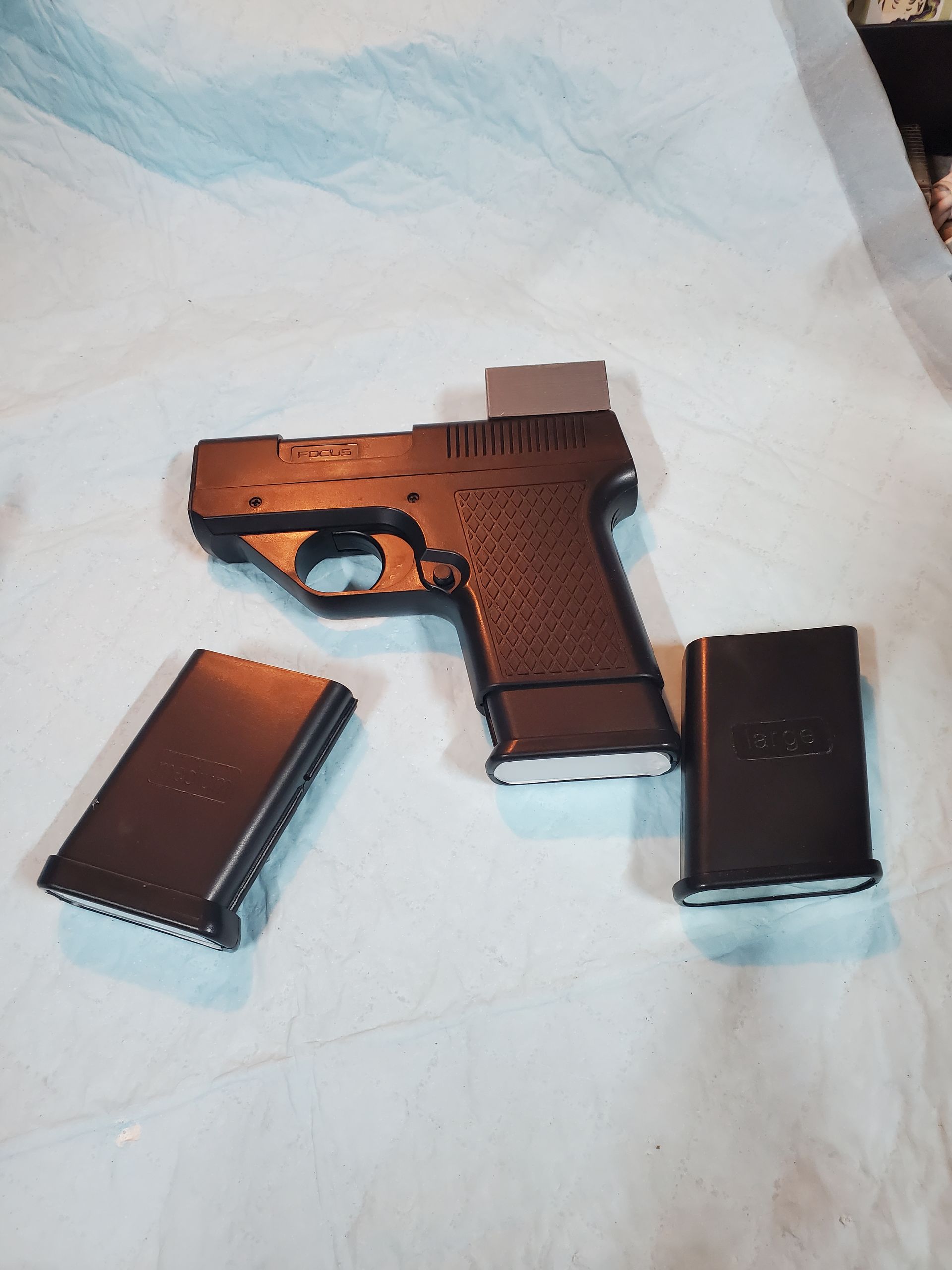 Brown handgun with two magazines on a light cloth background