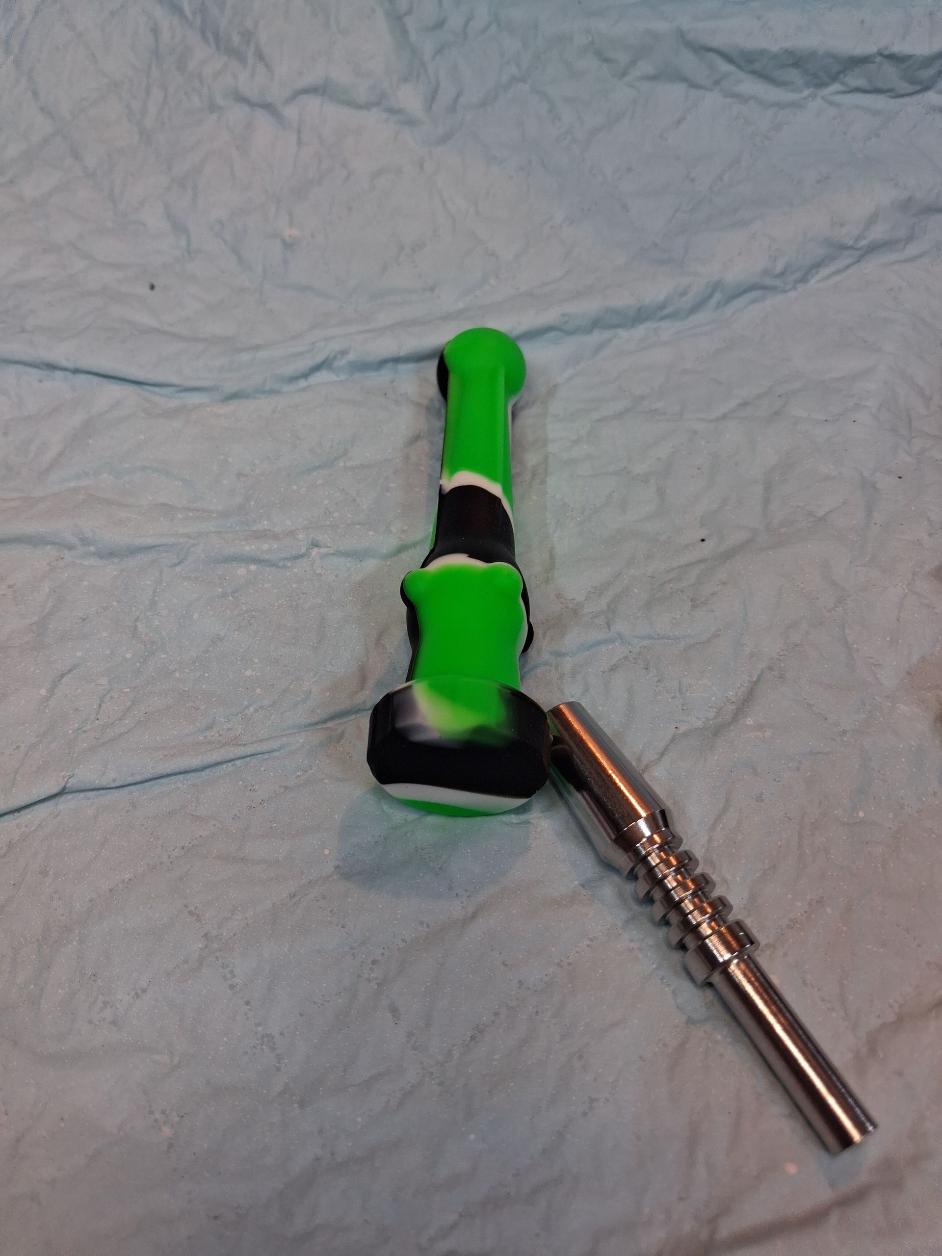 Green-and-black handle with a metal shaft lying on a light blue cloth background