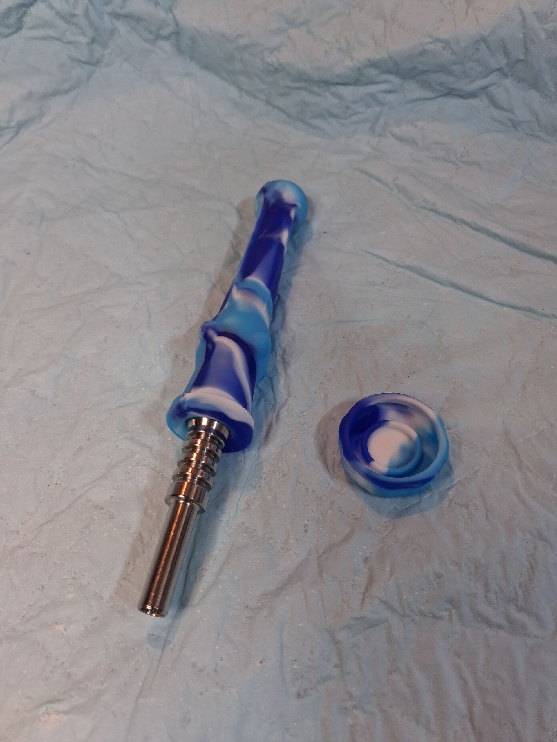 Blue and silver pen-like tool on a blue disposable drape, with a detached circular cap beside it