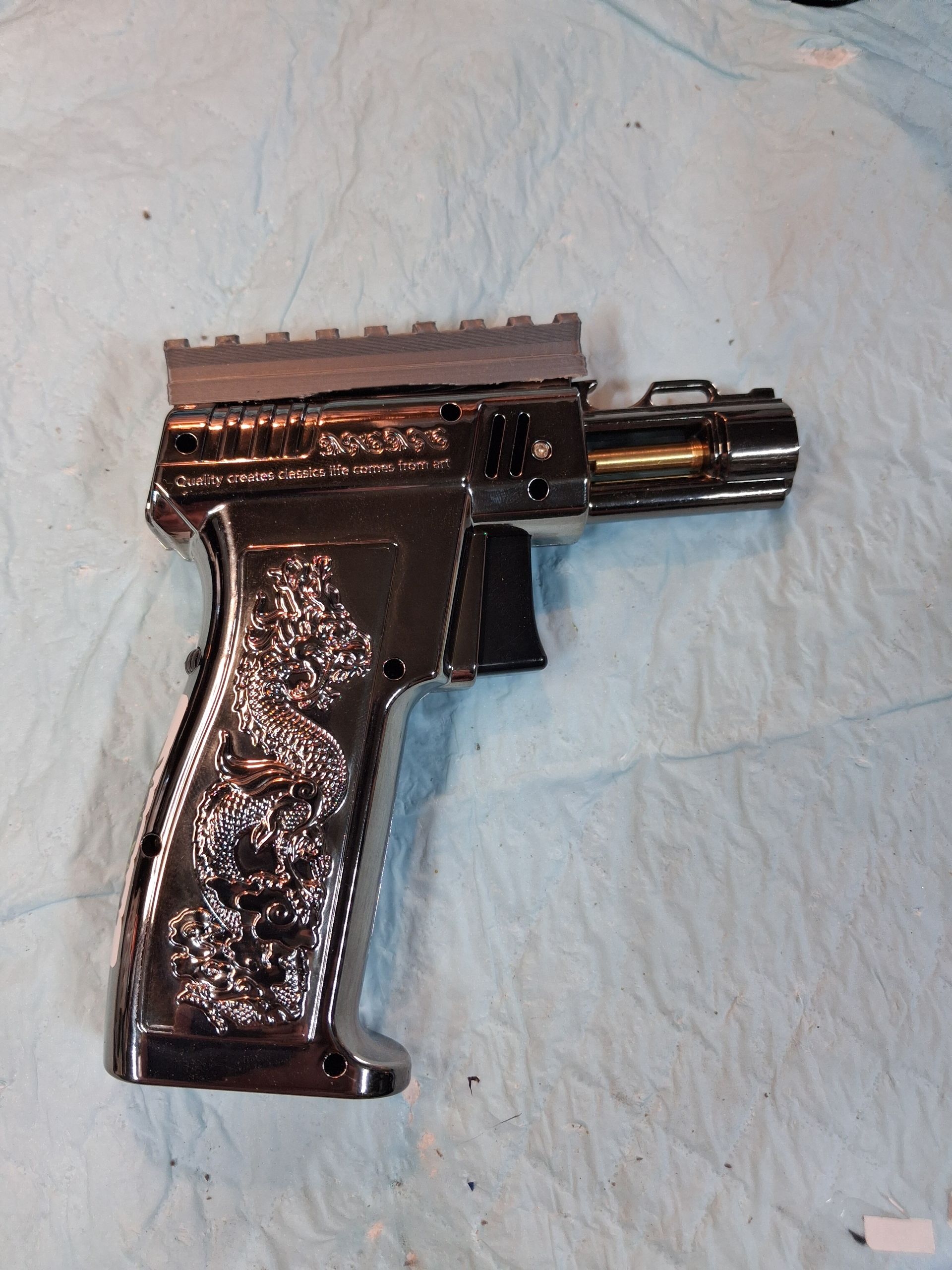 Black handgun with a reflective grip lying on a light blue cloth background