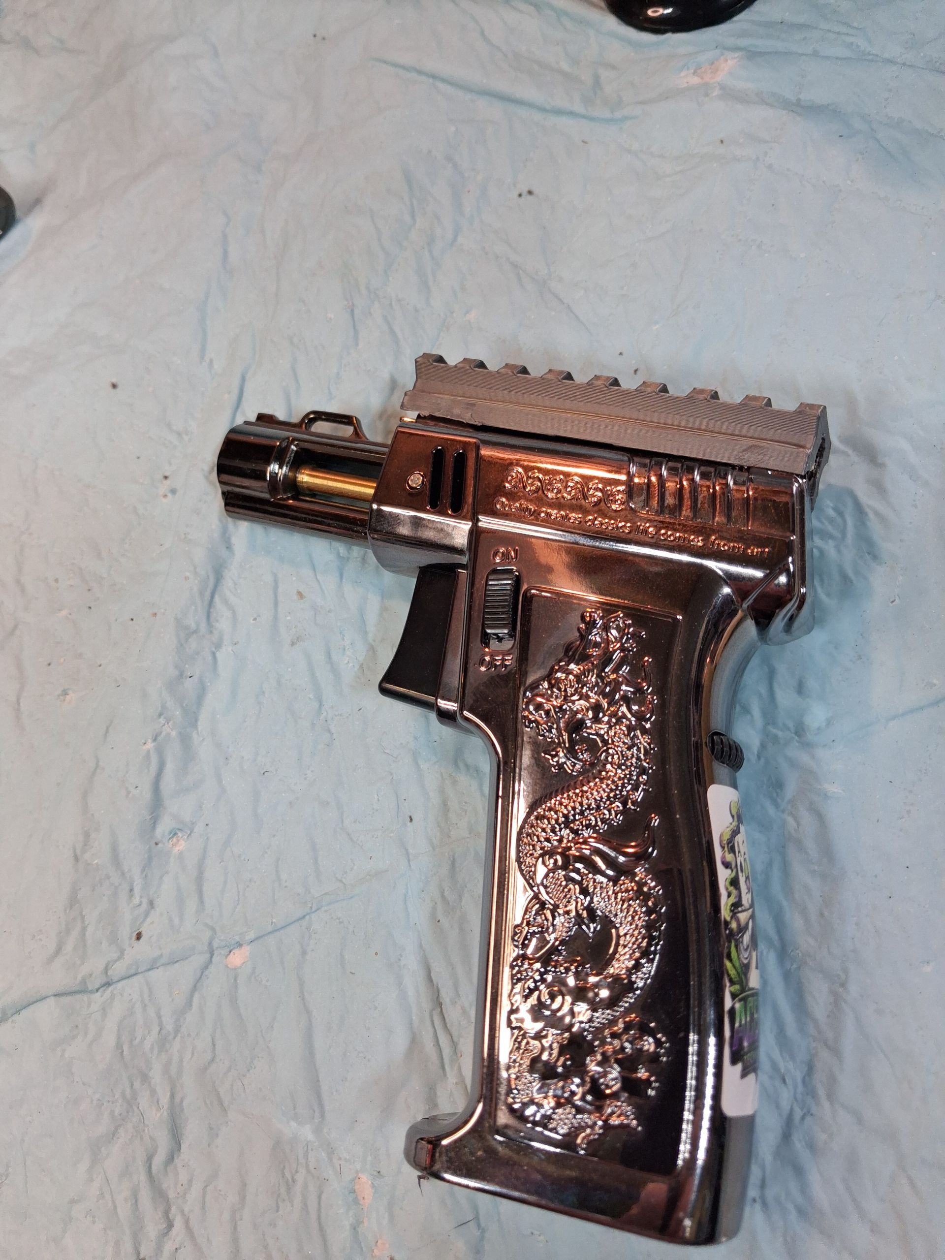 Black handgun with a reflective grip lying on a light blue cloth background