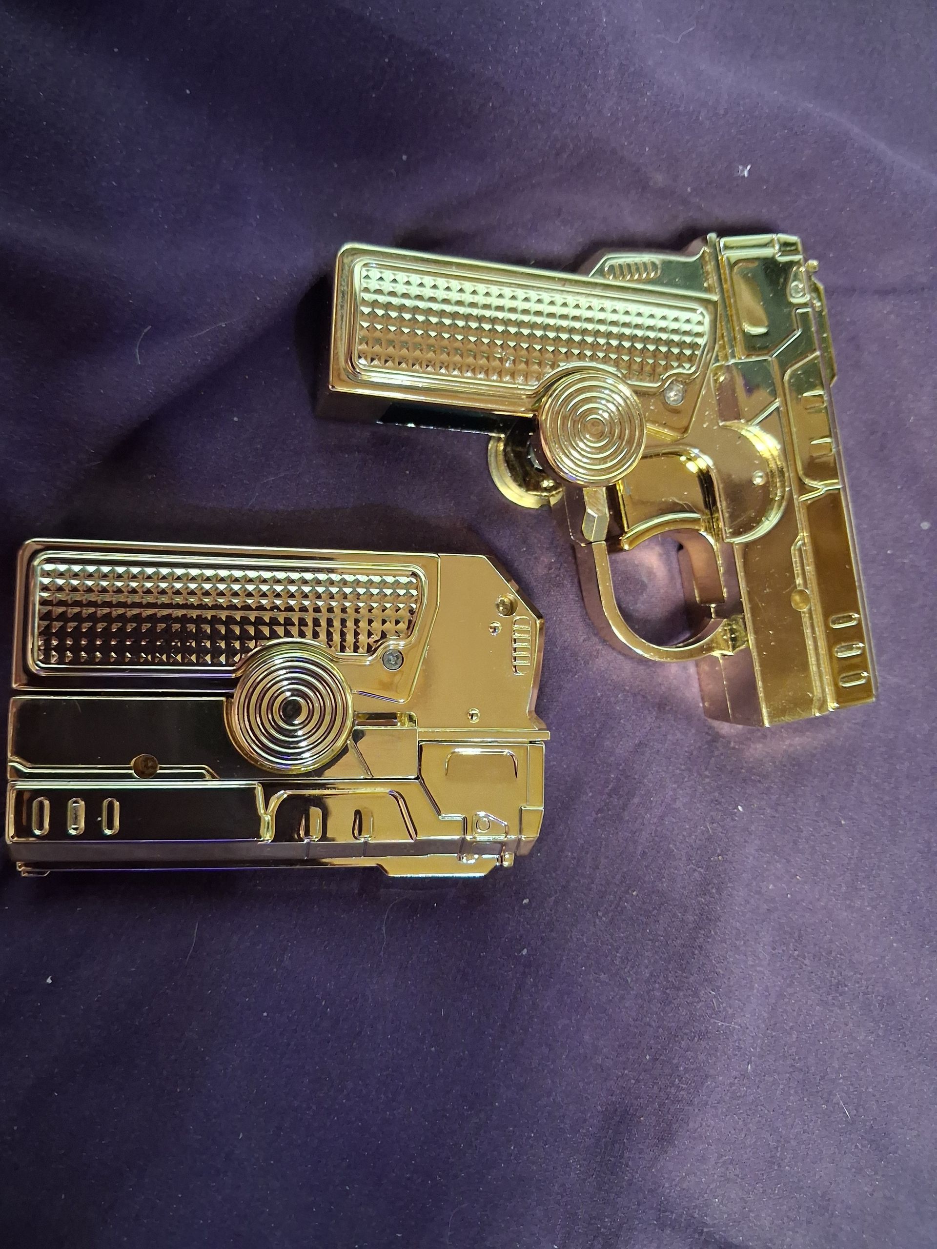 Three toy guns in gold, silver, and bronze on a purple cloth background