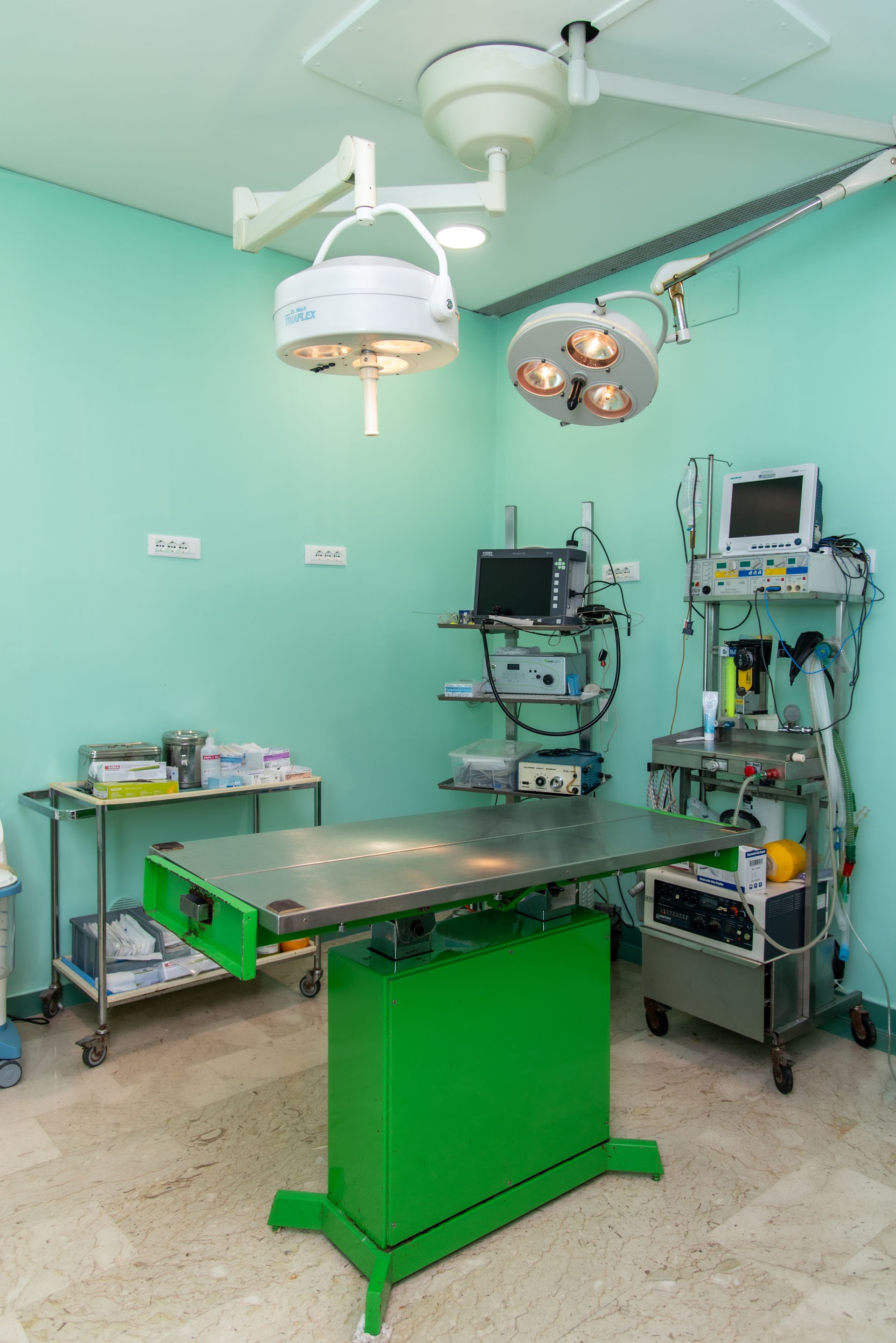 Una sala operatoria con un tavolo verde e un sacco di attrezzature.