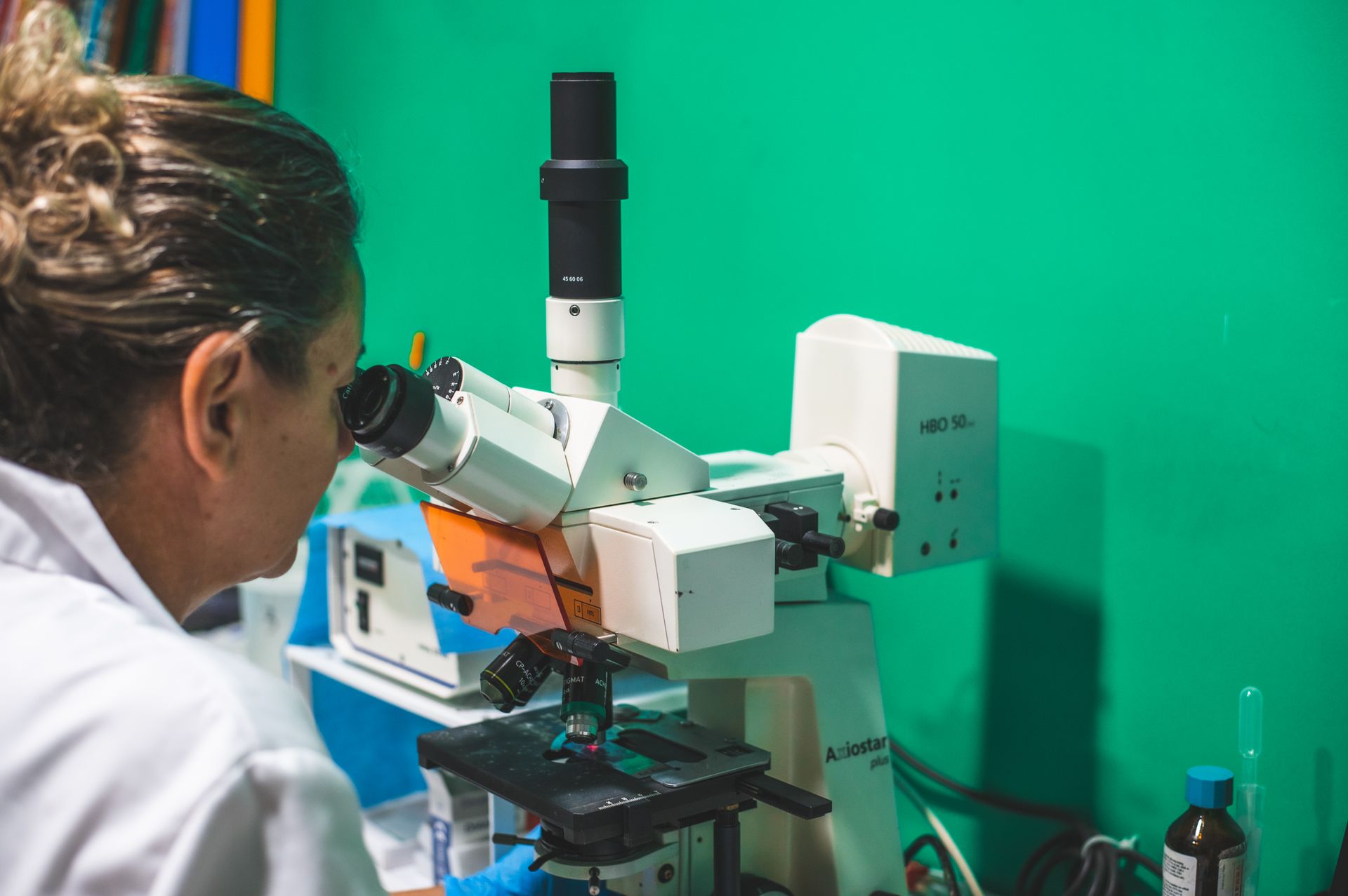 Una donna guarda attraverso un microscopio in un laboratorio.
