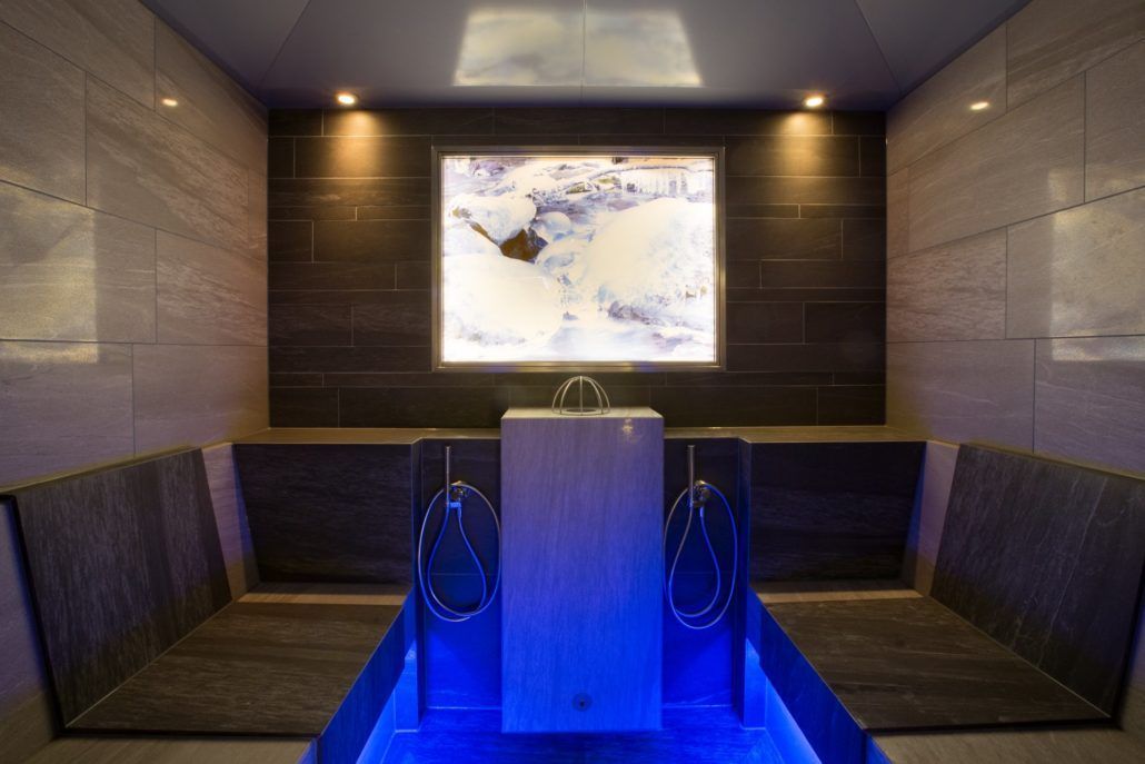 Eine Sauna mit blauem Licht auf dem Boden und Wandfliesen.