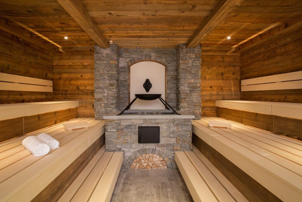 Eine Sauna mit Holzbänken und einem Natursteinkamin.