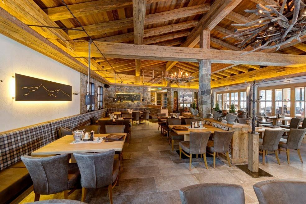 Ein Restaurant mit grauen Bodenfliesen, Tischen und Stühlen und einer Holzdecke.
