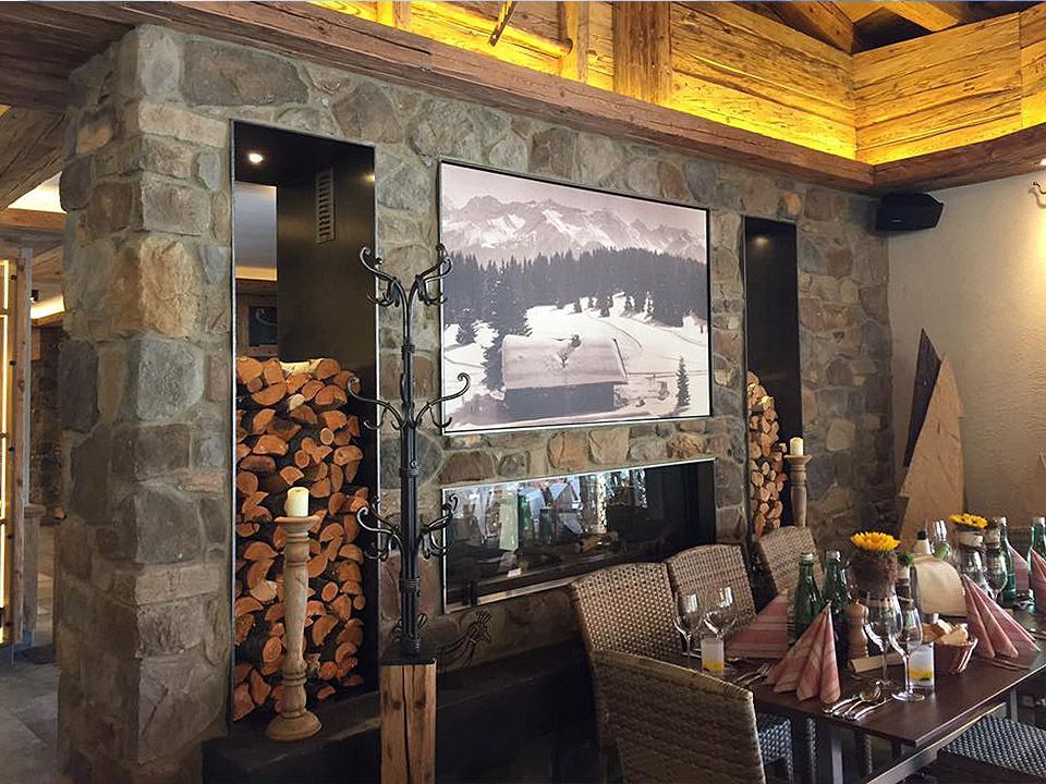 Ein Esszimmer mit Tisch und Stühlen und einem großen Bild an der Natursteinwand.
