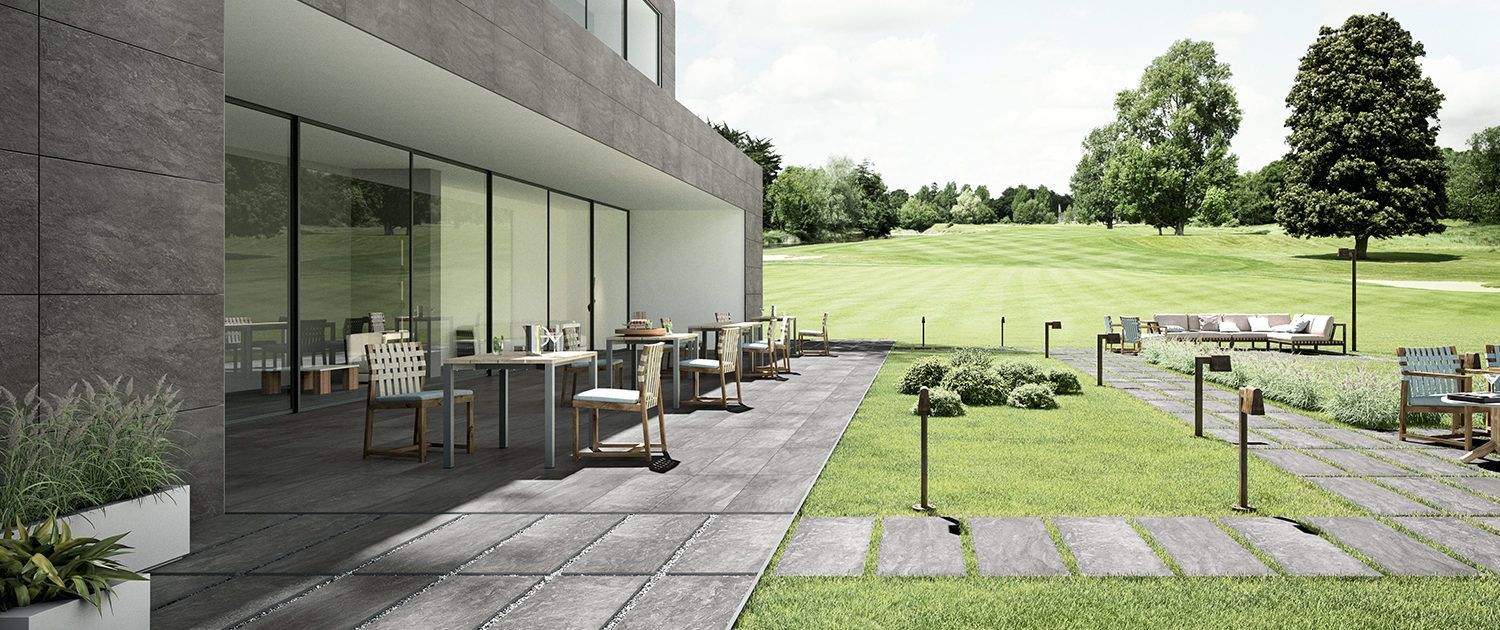 Eine Terrasse mit Tischen und Stühlen vor einem Gebäude mit einem Golfplatz im Hintergrund.