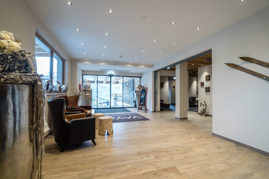Eine große Lobby mit Stuhl, Tisch und Skiern an der Wand.