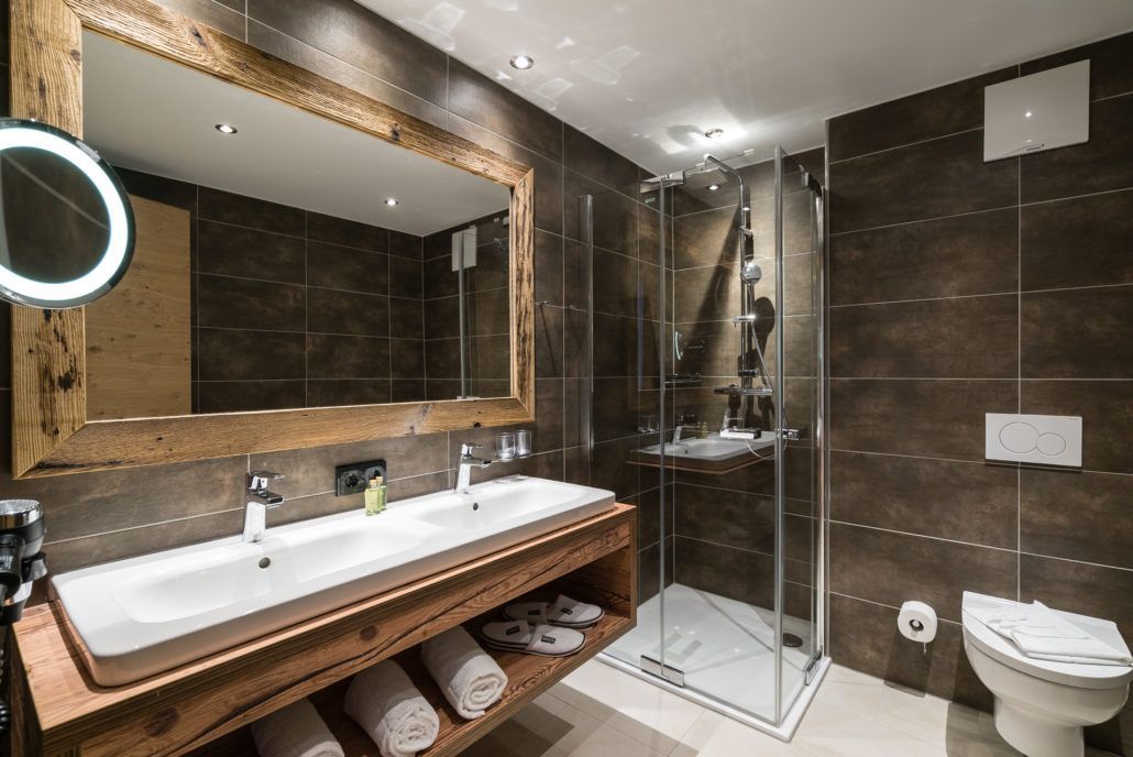Ein Badezimmer mit zwei Waschbecken, einer Toilette und einem großen Spiegel.
