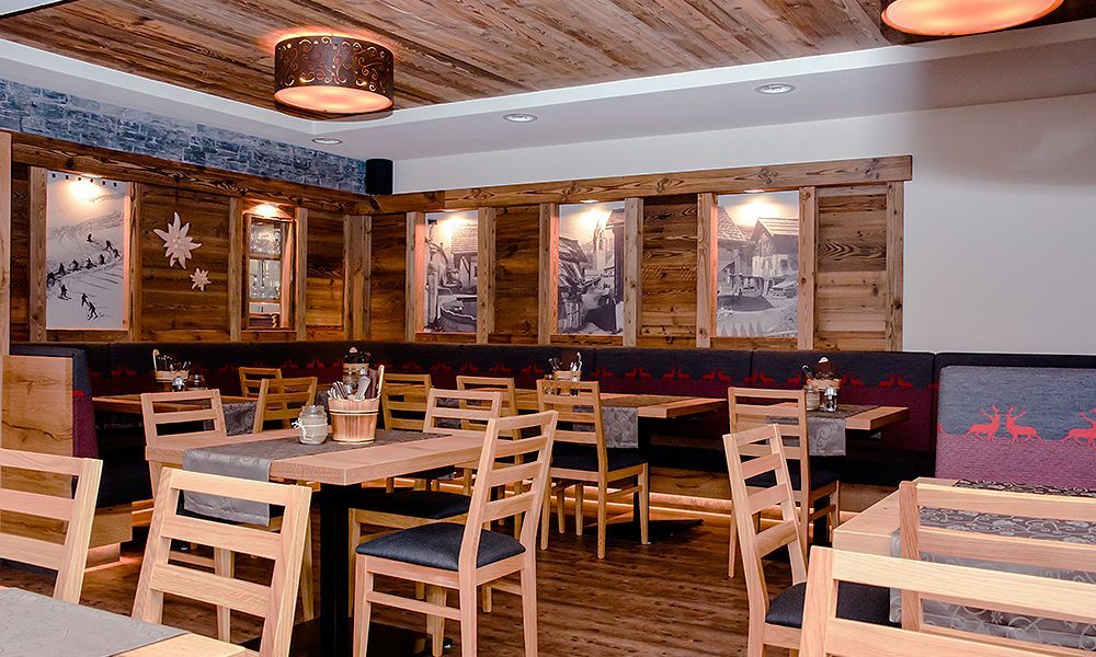 Ein Restaurant mit Bodenfliesen in Holzoptik, Holztischen und -stühlen und einer Holzdecke