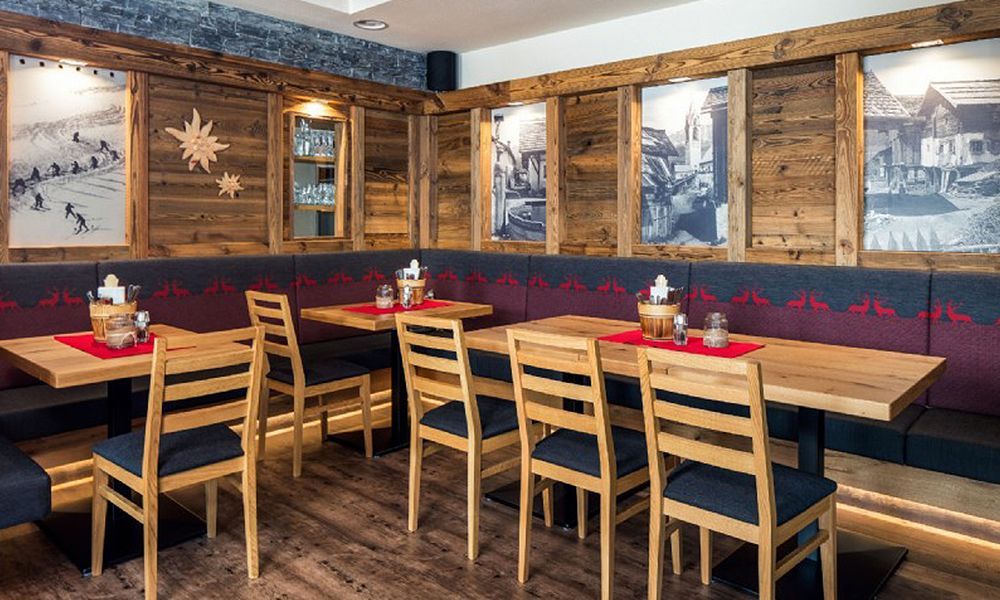 Ein Restaurant mit Bodenfliesen aus Holzoptik, Holztischen und -stühlen und Bildern an der Wand.