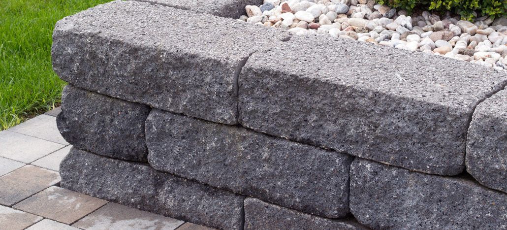 Eine Steinmauer als Begrenzung voller Steine ​​und einer Pflanze darin.