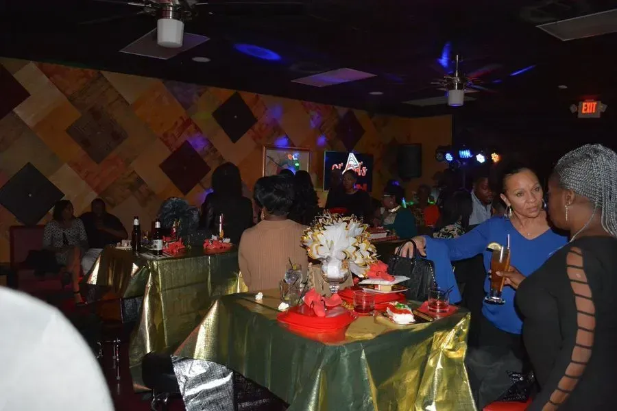 Dimly lit restaurant with people seated at tables, blue lights, and red-and-gold table settings.