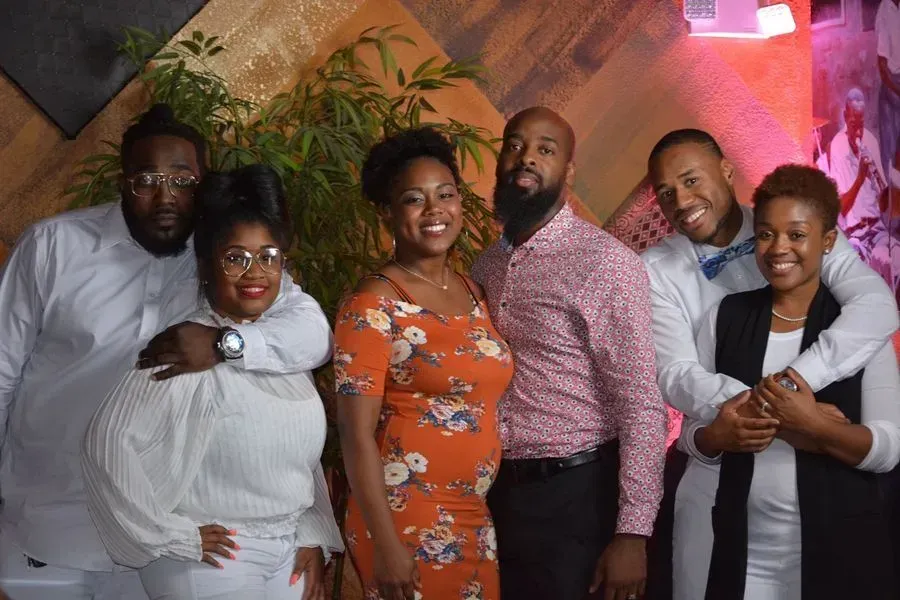 Five people smiling and posing together at a decorated indoor event