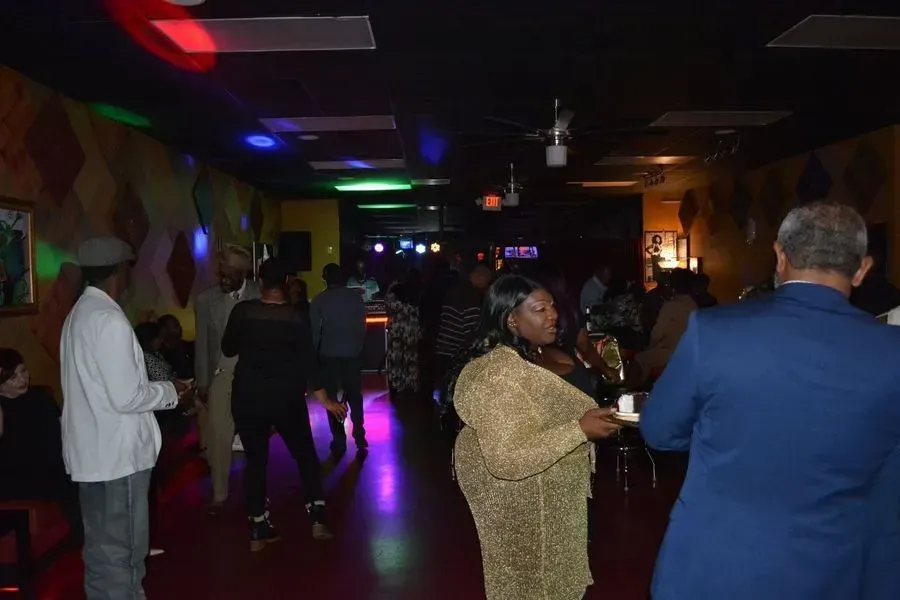 People dancing in a dimly lit club with colorful lights and reflections on the floor