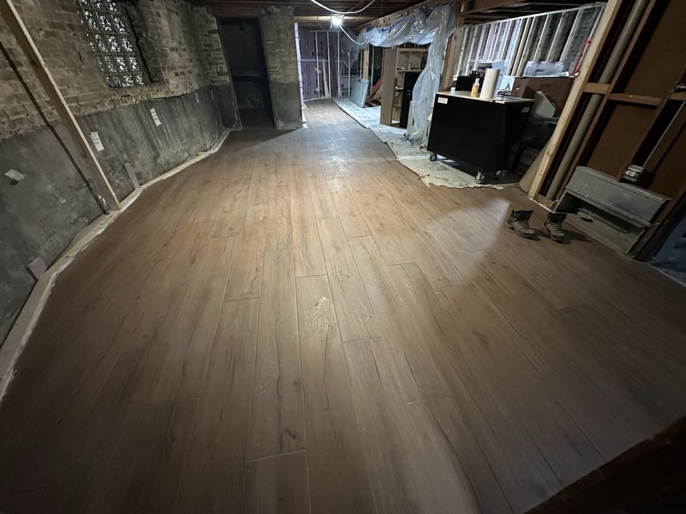 Empty basement room with unfinished walls and light wood flooring under construction